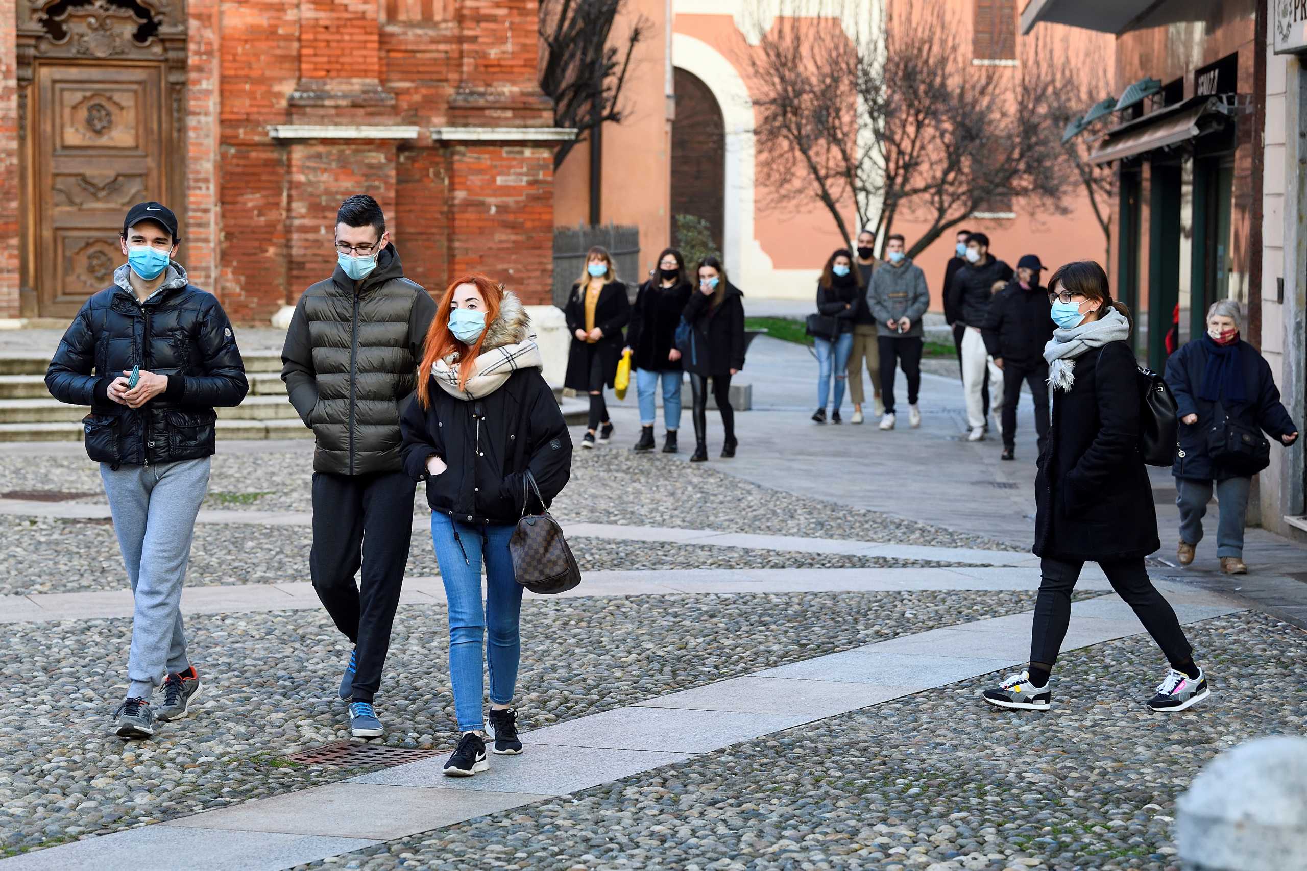 People wearing masks walk in a square in Codogno, one year after the small northern town became Europe's coronavirus disease (COVID-19) epicentre, in Codogno, Italy, February 11, 2021. Picture taken February 11, 2021. REUTERS