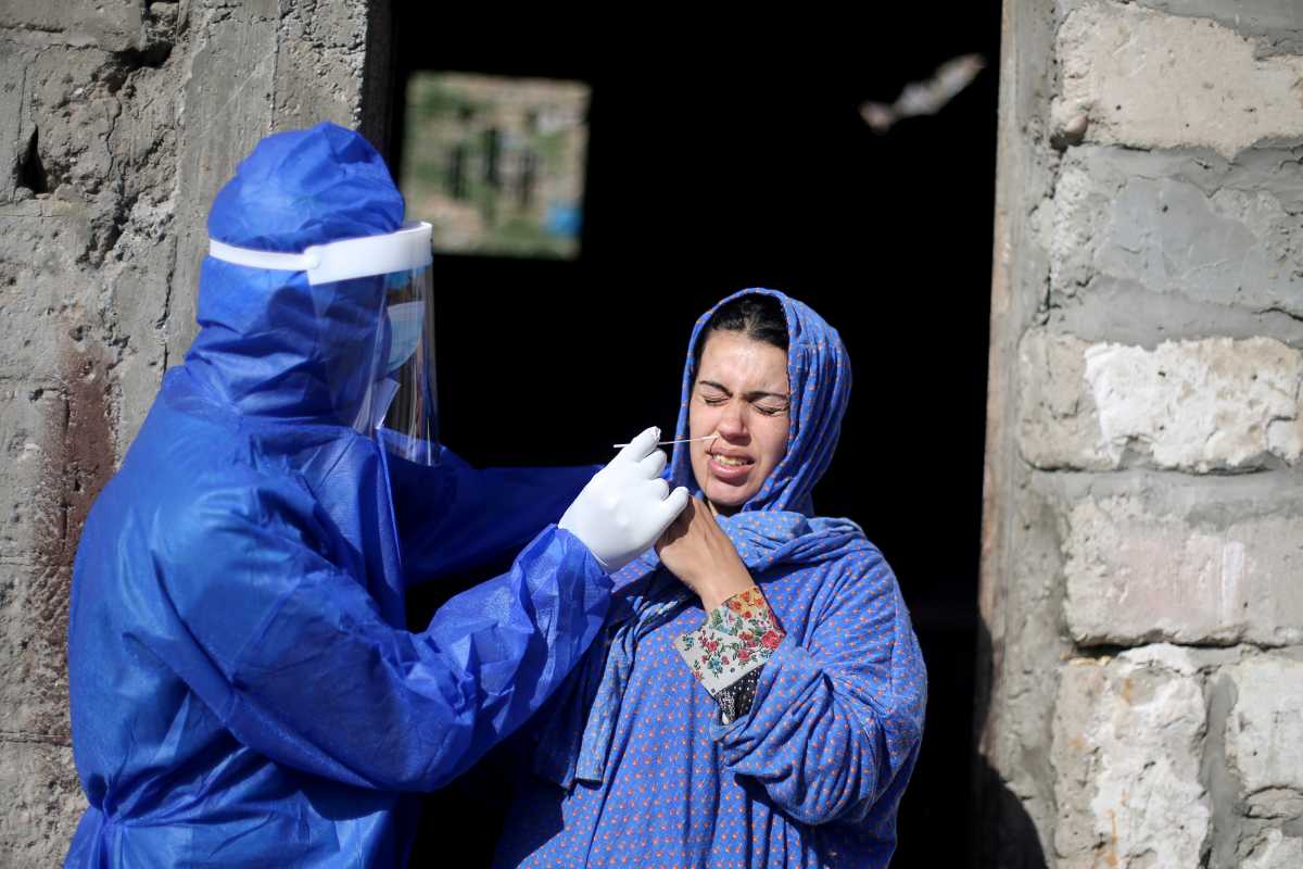 A medical worker collects a swab sample from a woman to be tested for the coronavirus disease (COVID-19), in the southern Gaza Strip January 14, 2021. Picture taken January 14, 2021. REUTERS