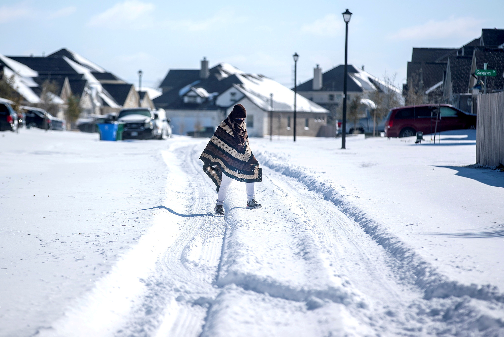 FILE PHOTO: A man walks to his friend's home in a neighbourhood without electricity as snow covers the BlackHawk neighborhood in Pflugerville, Texas, U.S. February 15, 2021. Bronte Wittpenn