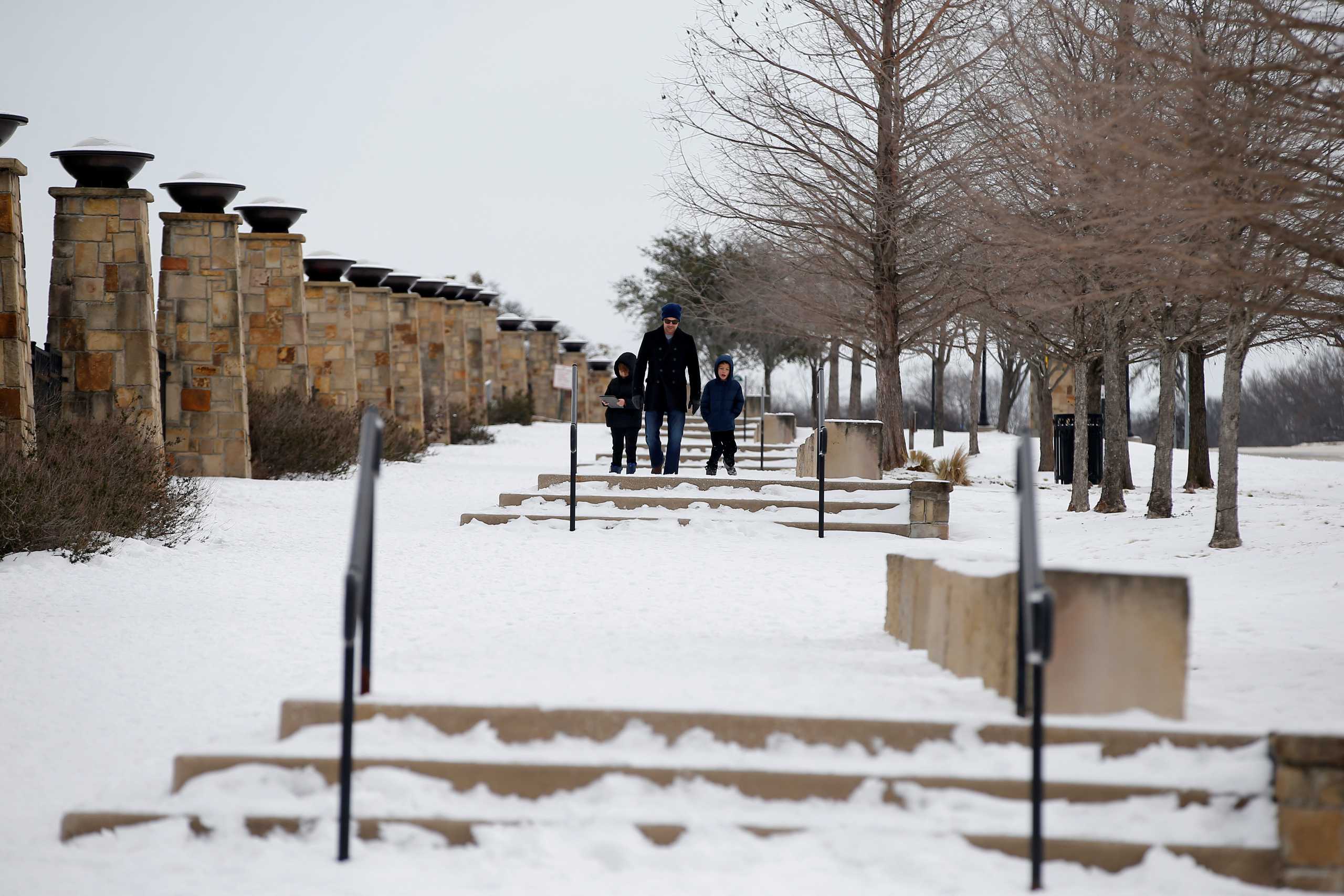 Will Moore, center, enjoys the snow-covered White Rock Lake with his kids Fin,10, left, and Fisher, 8, after winter weather caused electricity blackouts in Dallas, Texas, U.S. February 18, 2021.  REUTERS