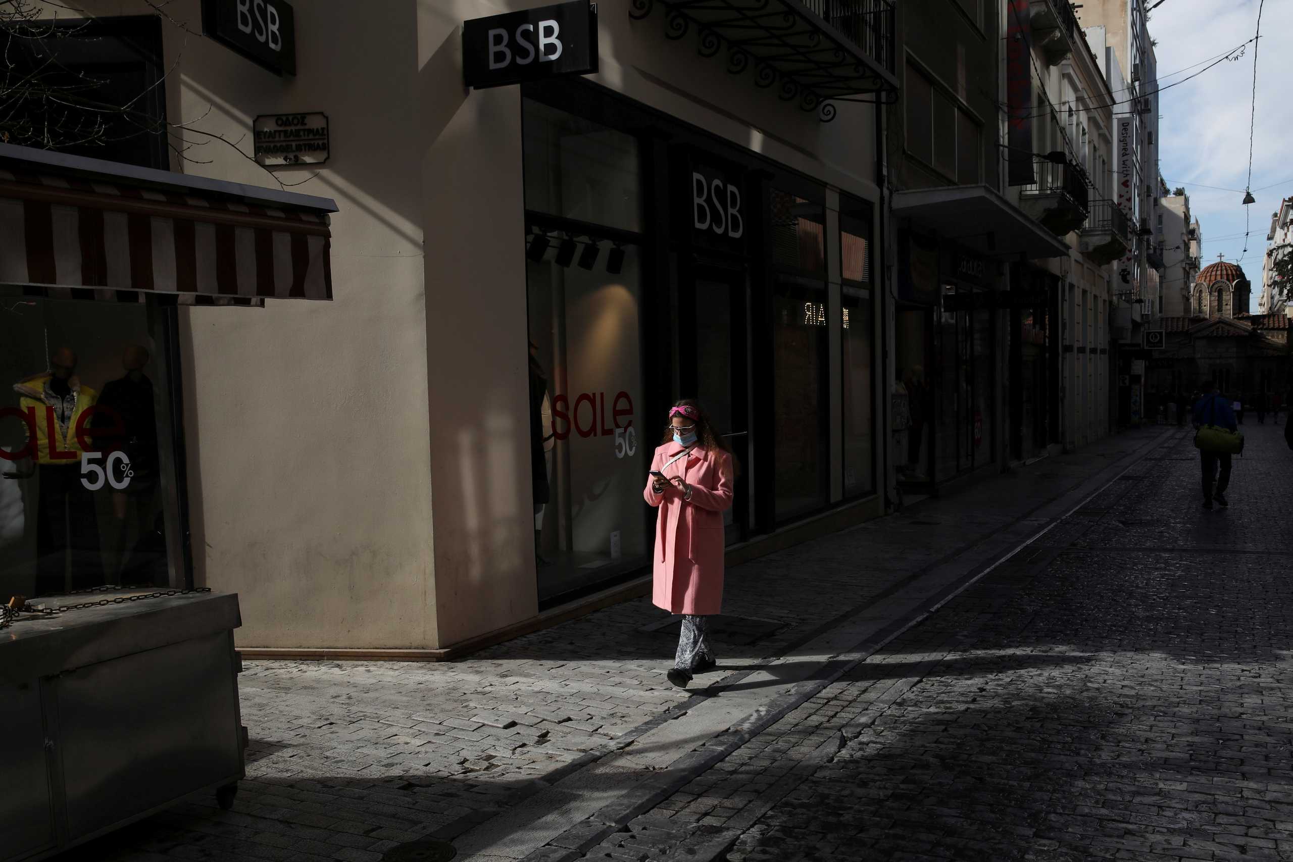 A woman wearing a protective face mask walks past closed shops, amid lockdown restrictions due to the spread of the coronavirus disease (COVID-19) pandemic, in Athens, Greece, February 6, 2021. REUTERS