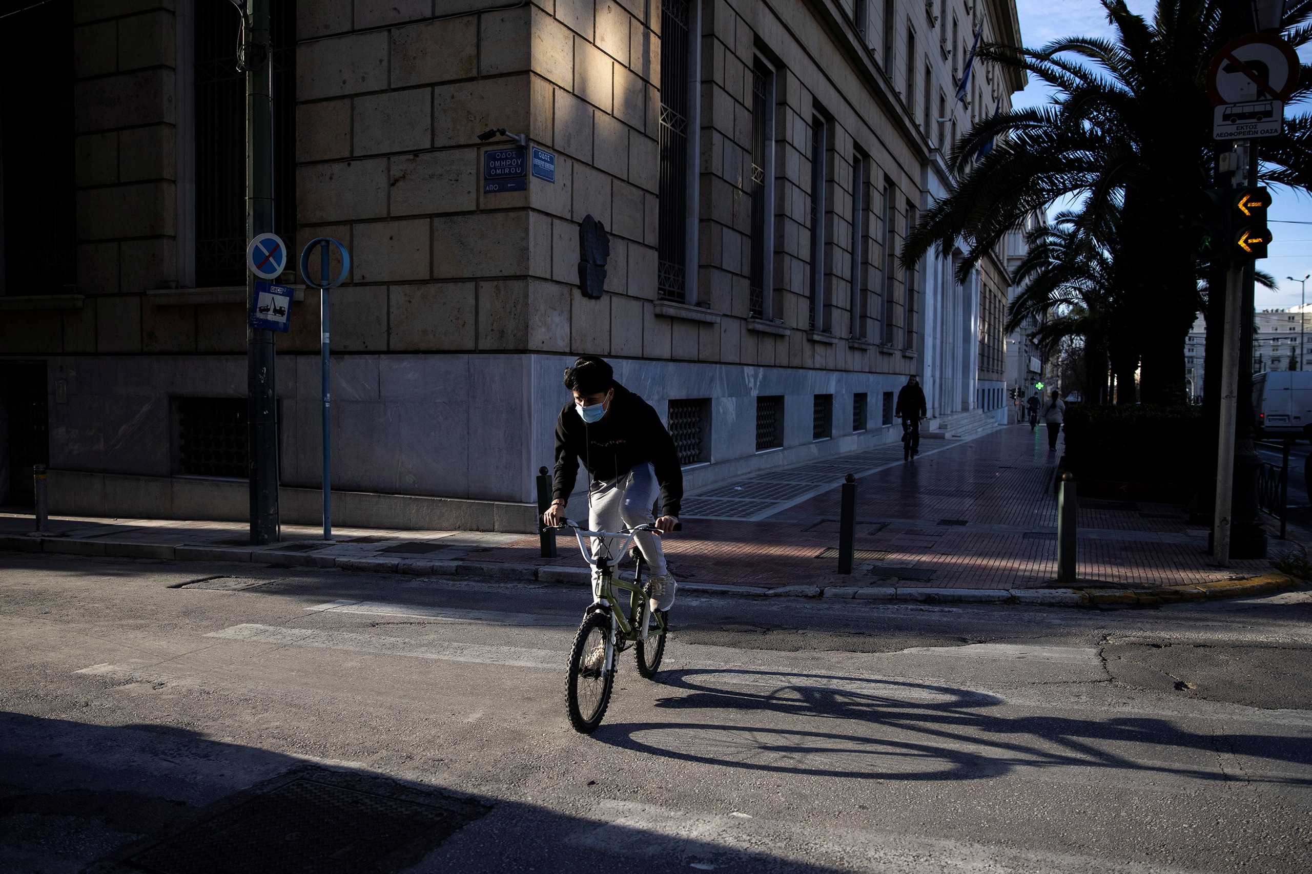 A boy wearing a protective face mask rides his bike, amid the coronavirus disease (COVID-19) pandemic, in Athens, Greece, February 2, 2021. REUTERS