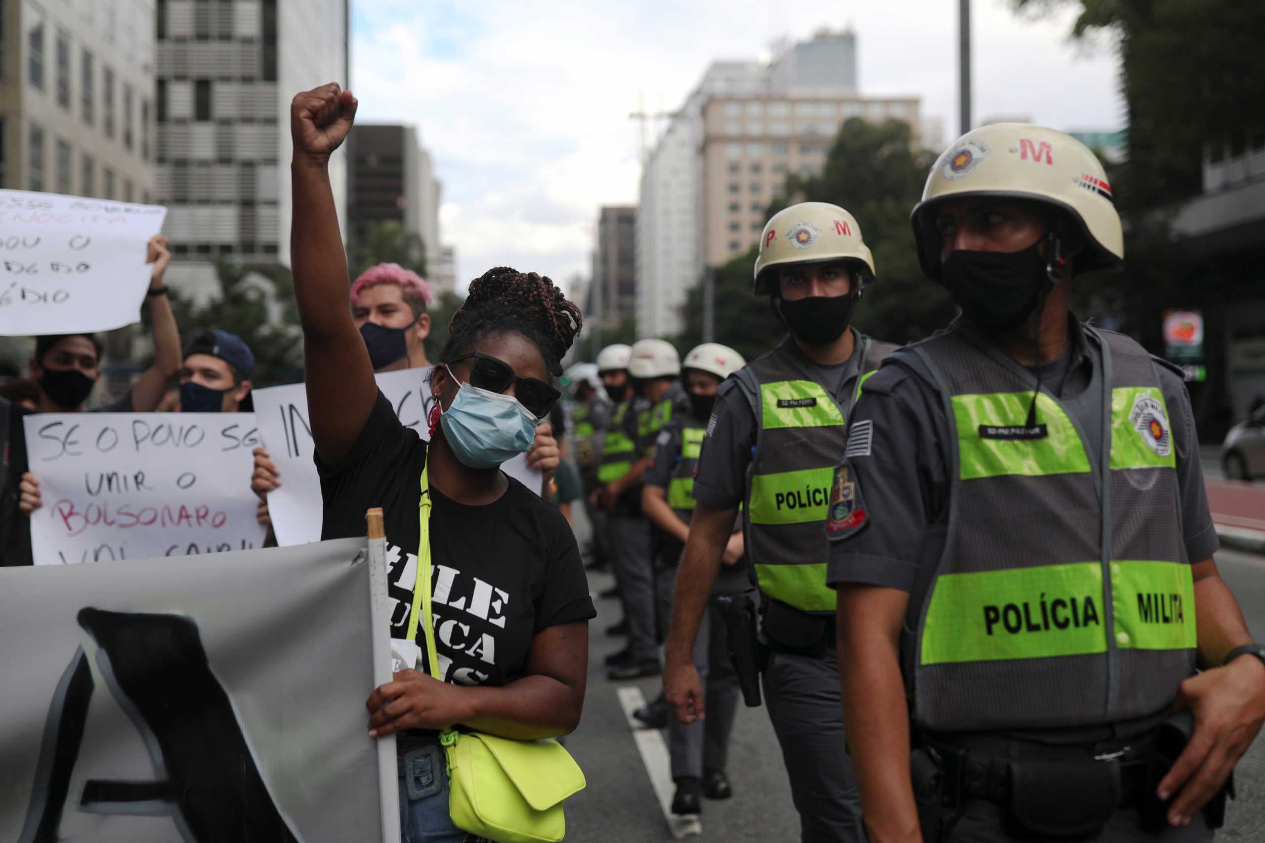 Demonstrators stand next to police officers during a protest against Brazil's President Jair Bolsonaro and his handling of the coronavirus disease (COVID-19) outbreak, in Sao Paulo, Brazil, January 31, 2021. REUTERS
