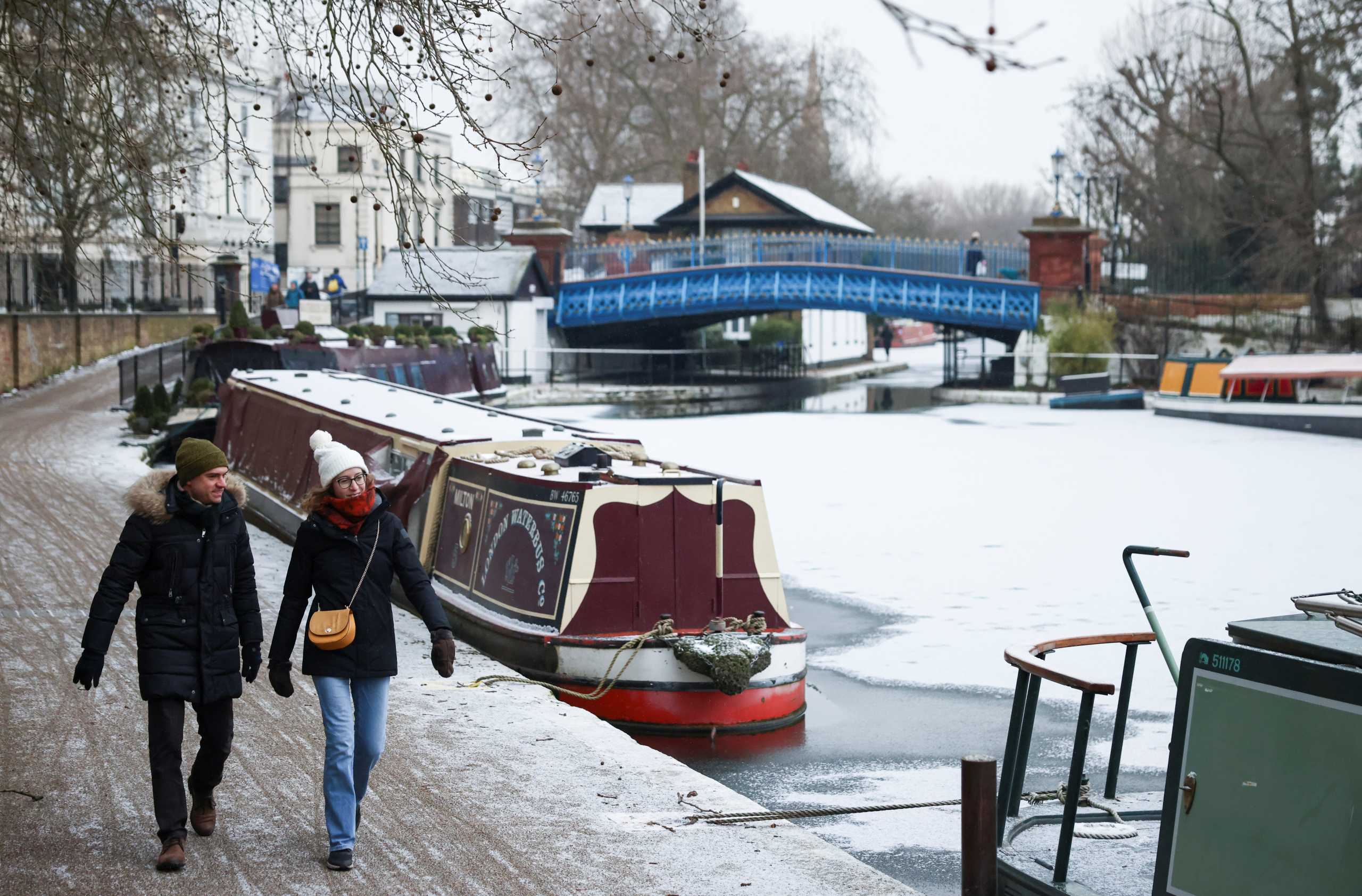 People stroll along a frozen canal and narrow boats in Little Venice, London, Britain February 11, 2021. REUTERS