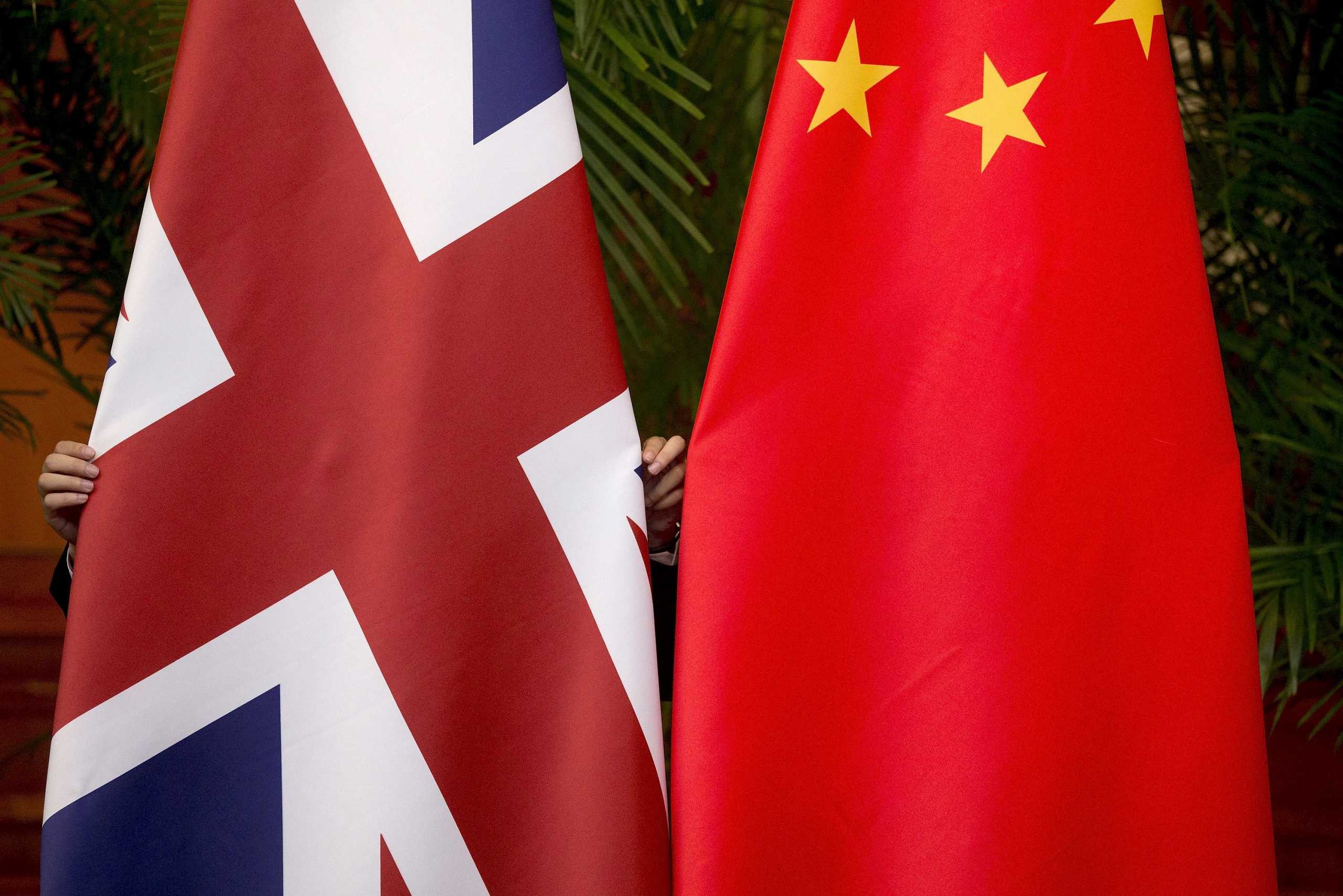 FILE PHOTO: A worker adjusts British and China (R) national flags on display for a signing ceremony at the seventh UK-China Economic and Financial Dialogue "Roundtable on Public-Private Partnerships" at Diaoyutai State Guesthouse in Beijing, China September 21, 2015. REUTERS