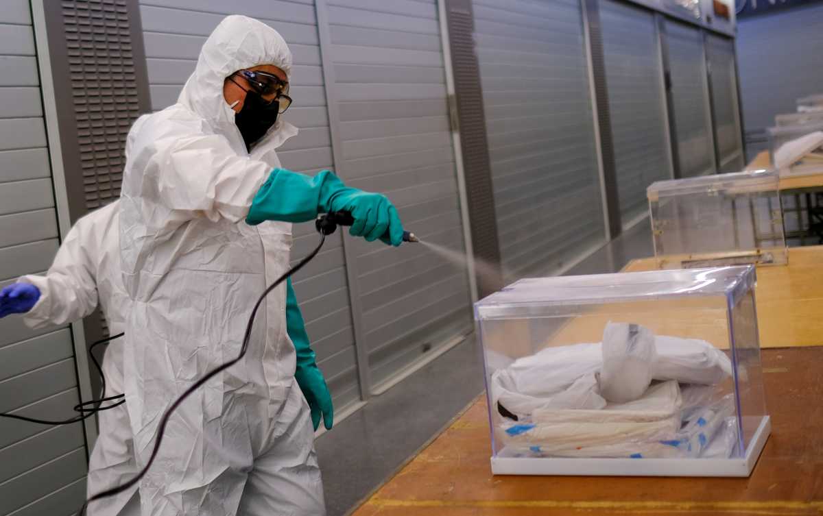 A worker uses disinfectant to clean ballot boxes containing personal protective equipment (PPE) supplies at Sant Antoni Market, which will be a polling station for the February 14th regional election, during the coronavirus disease (COVID-19) outbreak in Barcelona, Spain February 13, 2021.  REUTERS