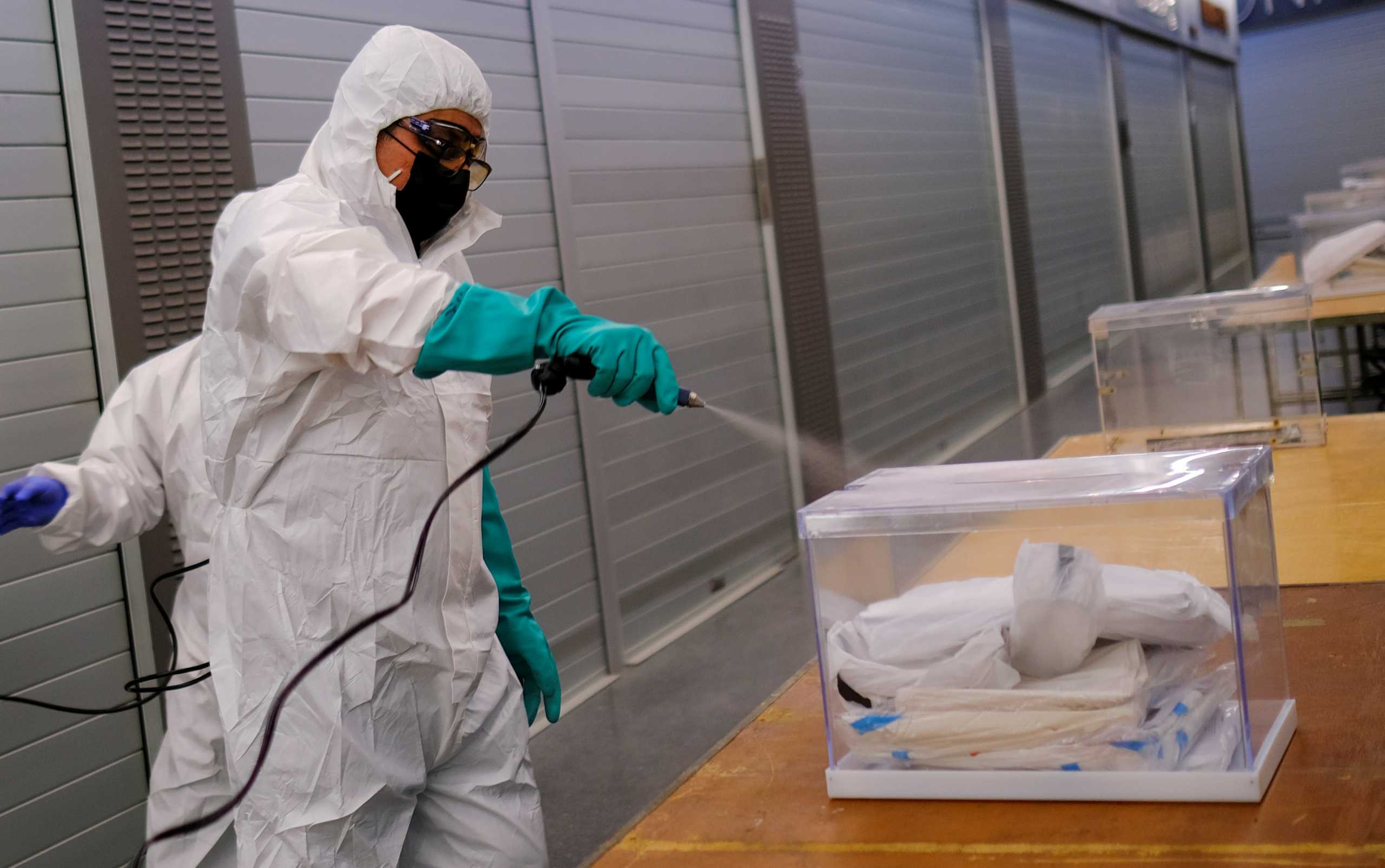 A worker uses disinfectant to clean ballot boxes containing personal protective equipment (PPE) supplies at Sant Antoni Market, which will be a polling station for the February 14th regional election, during the coronavirus disease (COVID-19) outbreak in Barcelona, Spain February 13, 2021.  REUTERS