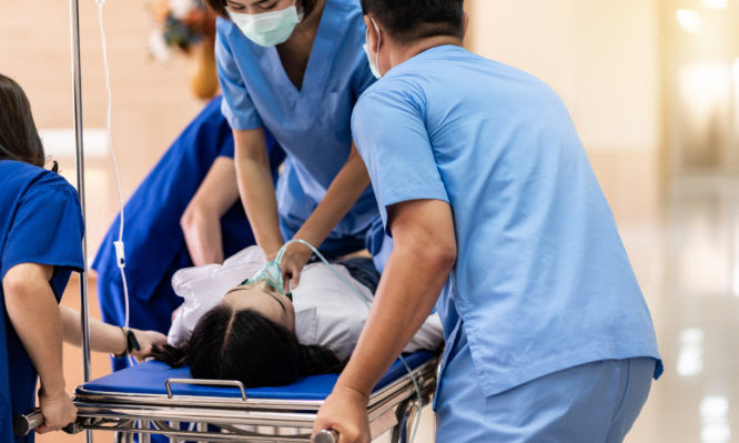 Medical team do CPR Cardiopulmonary resuscitation to seriously injured patient with oxygen mask while push gurney stretcher bed to Operating Room. Emergency health care and medical hospital concept.