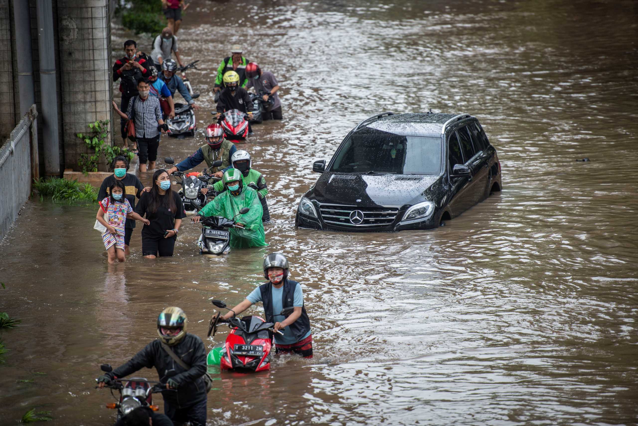 People push their motorbikes through water in an area affected by floods following heavy rains in Jakarta, Indonesia, February 20, 2021 in this photo taken by Antara Foto.  Antara Foto