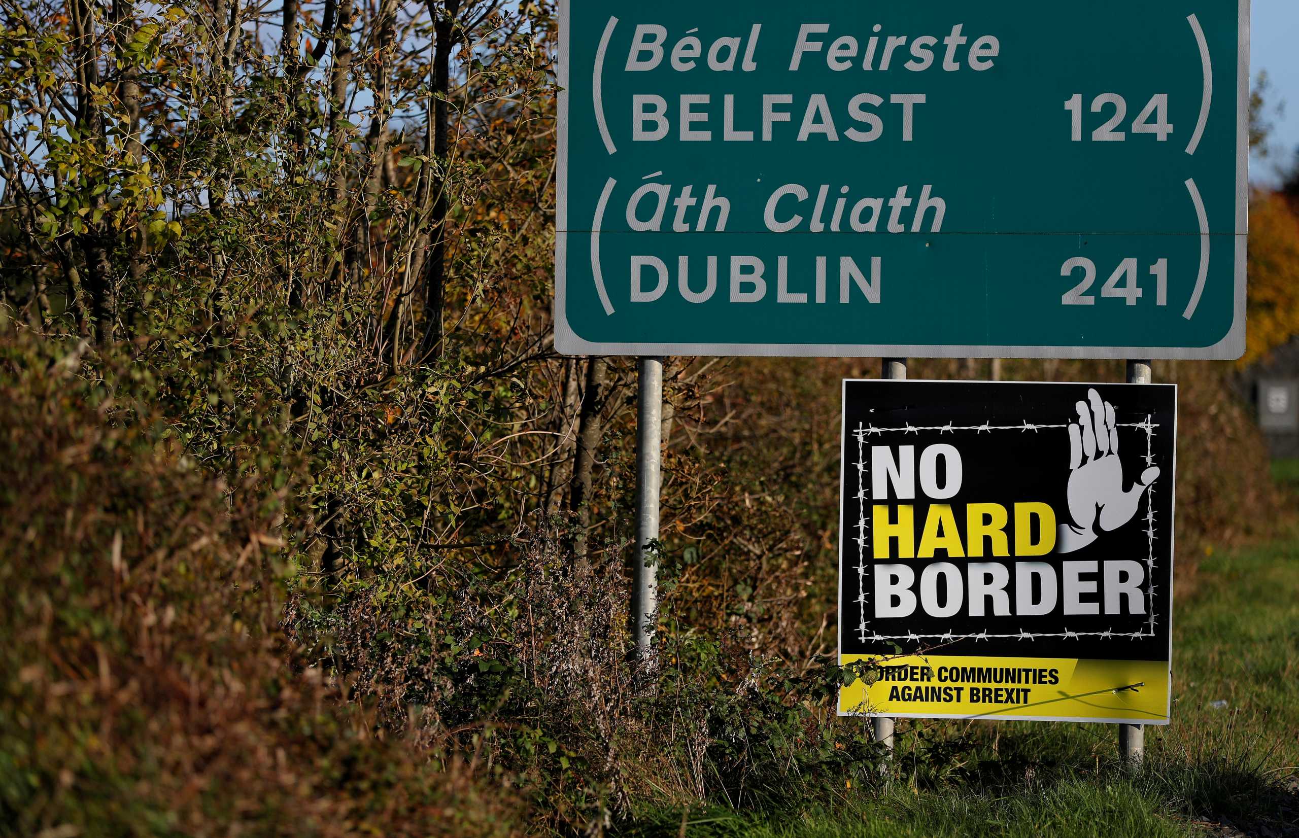FILE PHOTO: A 'No Hard Border' poster is seen below a road sign on the Irish side of the border between Ireland and Northern Ireland near Bridgend, Ireland October 16, 2019. Picture taken October 16, 2019. REUTERS