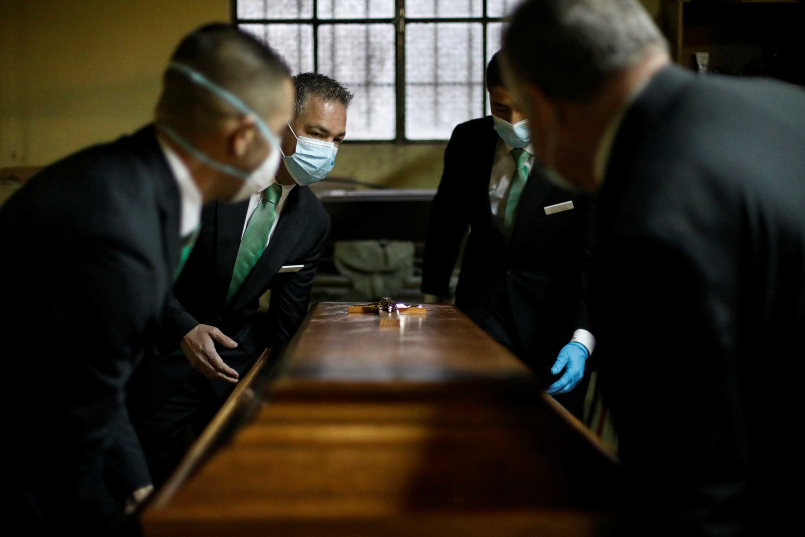 Funeral workers carry a coffin during the coronavirus disease (COVID-19) pandemic in Cascais, Portugal, February 9, 2021. Picture taken February 9, 2021. REUTERS