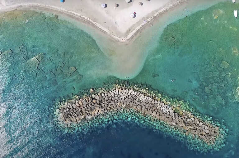 Η άγνωστη παραλία με τον περίεργο κυματοθράστη σε σχήμα «μπανάνας»