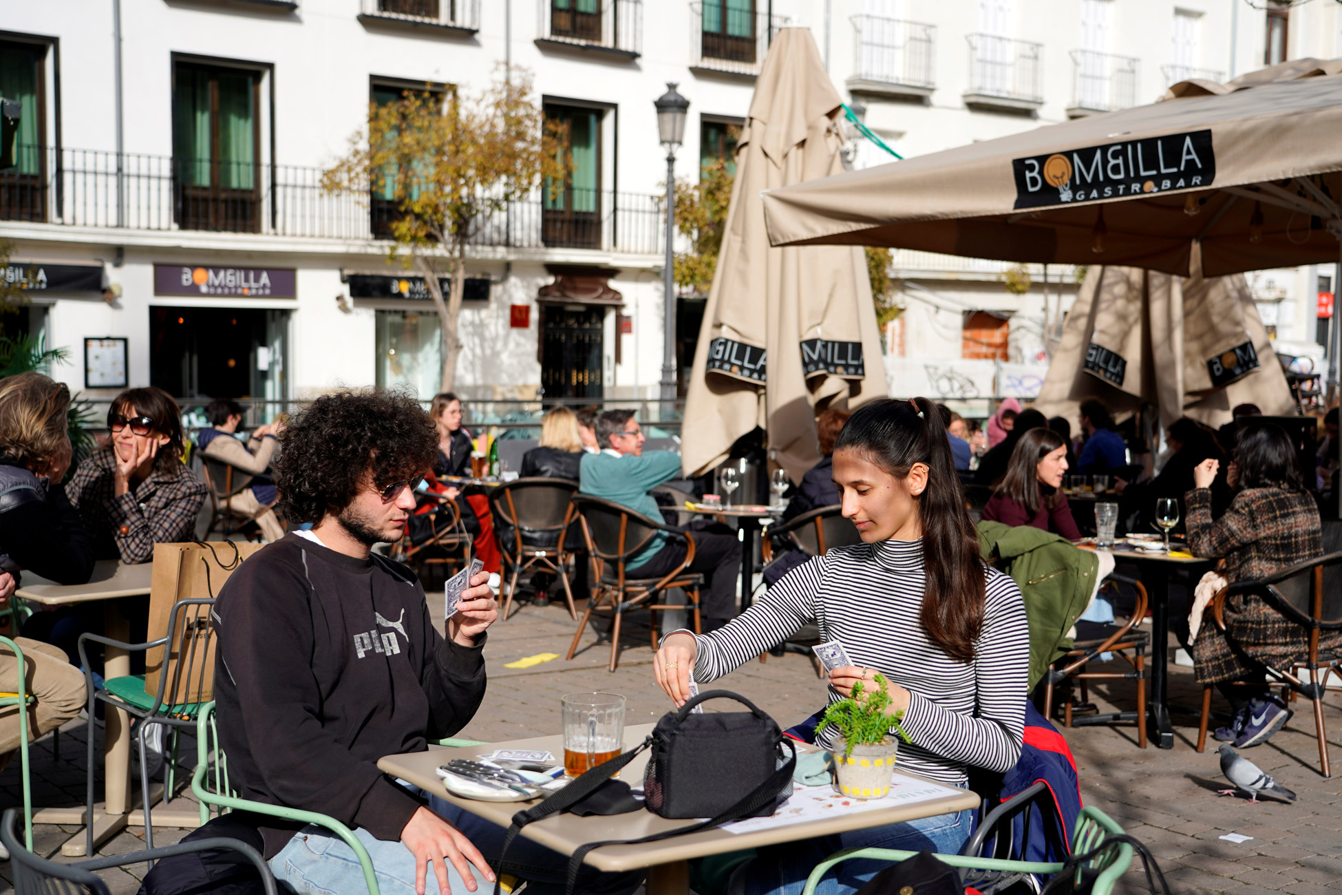 French visitors Theo Perucci and his sister Luna play cards while enjoying a meal on a terrace during their week on holiday as the coronavirus disease (COVID-19) pandemic continues in Madrid, Spain, February 5, 2021. Picture taken February 5, 2021. REUTERS