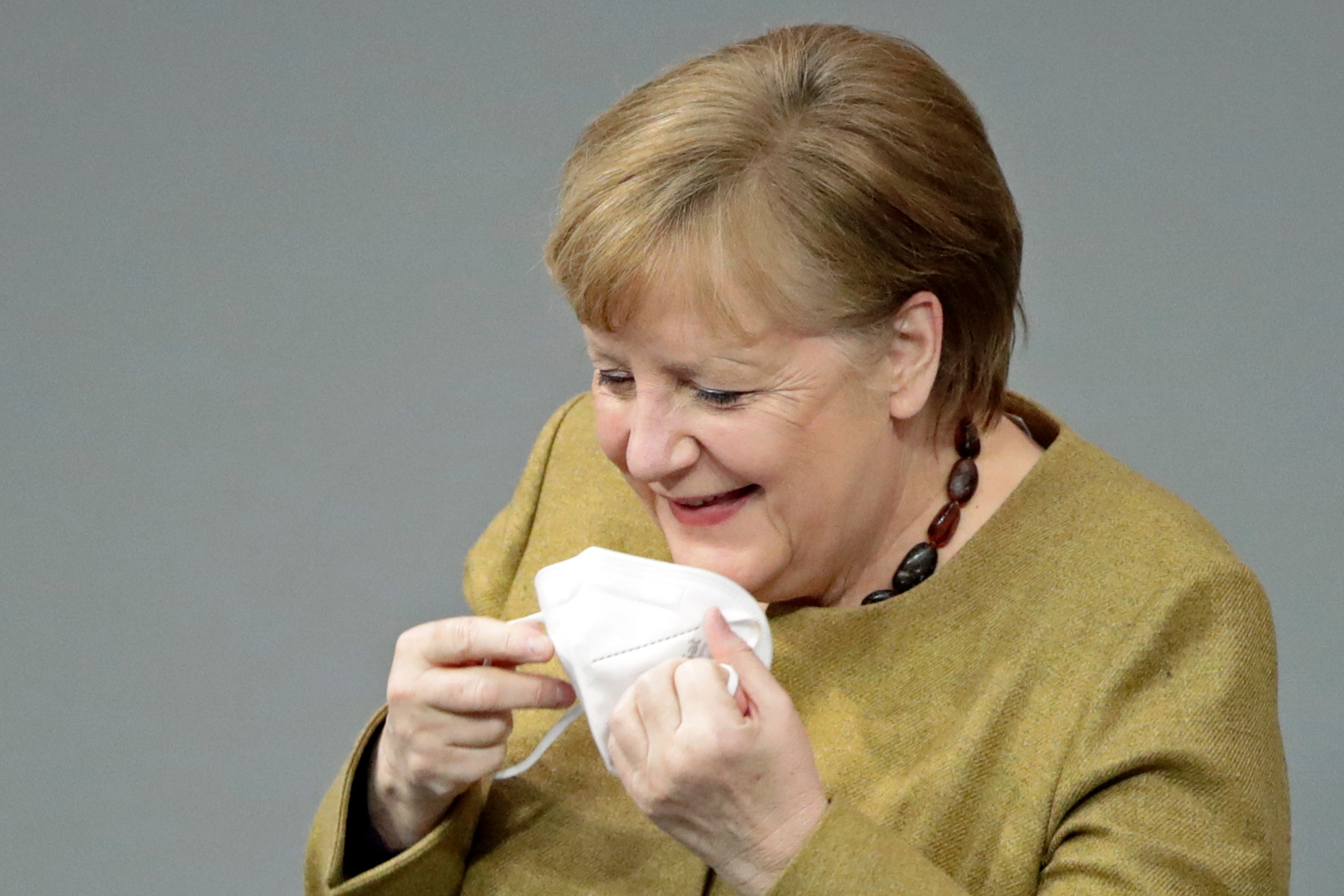 German Chancellor Angela Merkel holds her mask at the country's parliament, the Bundestag, in Berlin, Germany, February 11, 2021. REUTERS
