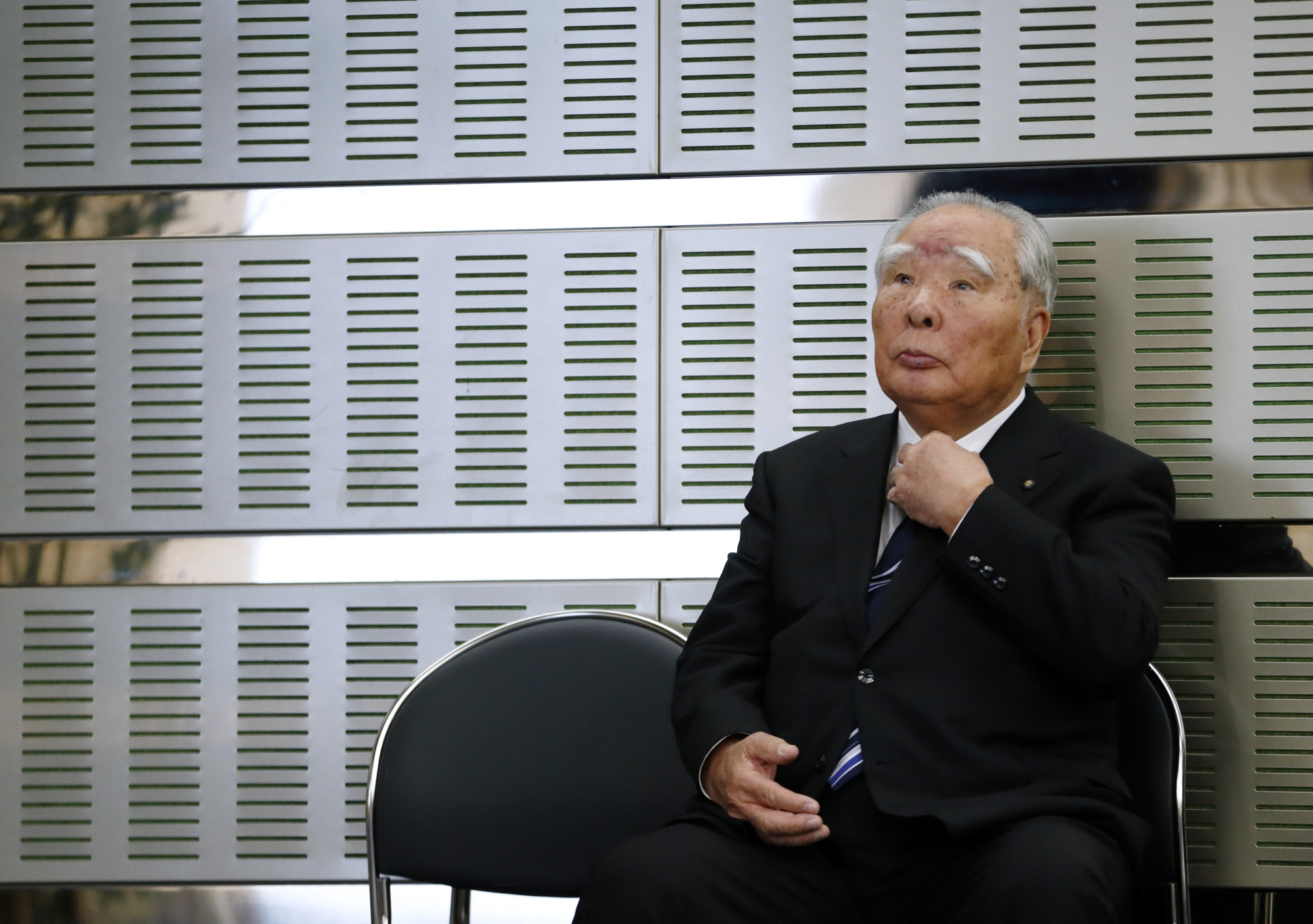 Osamu Suzuki, chairman of Suzuki Motor Corp., adjusts his tie during a news conference with Akio Toyoda, president of Toyota Motor Corp., not pictured, in Tokyo, Japan, on Wednesday, Oct. 12, 2016. Photographer: Tomohiro Ohsumi