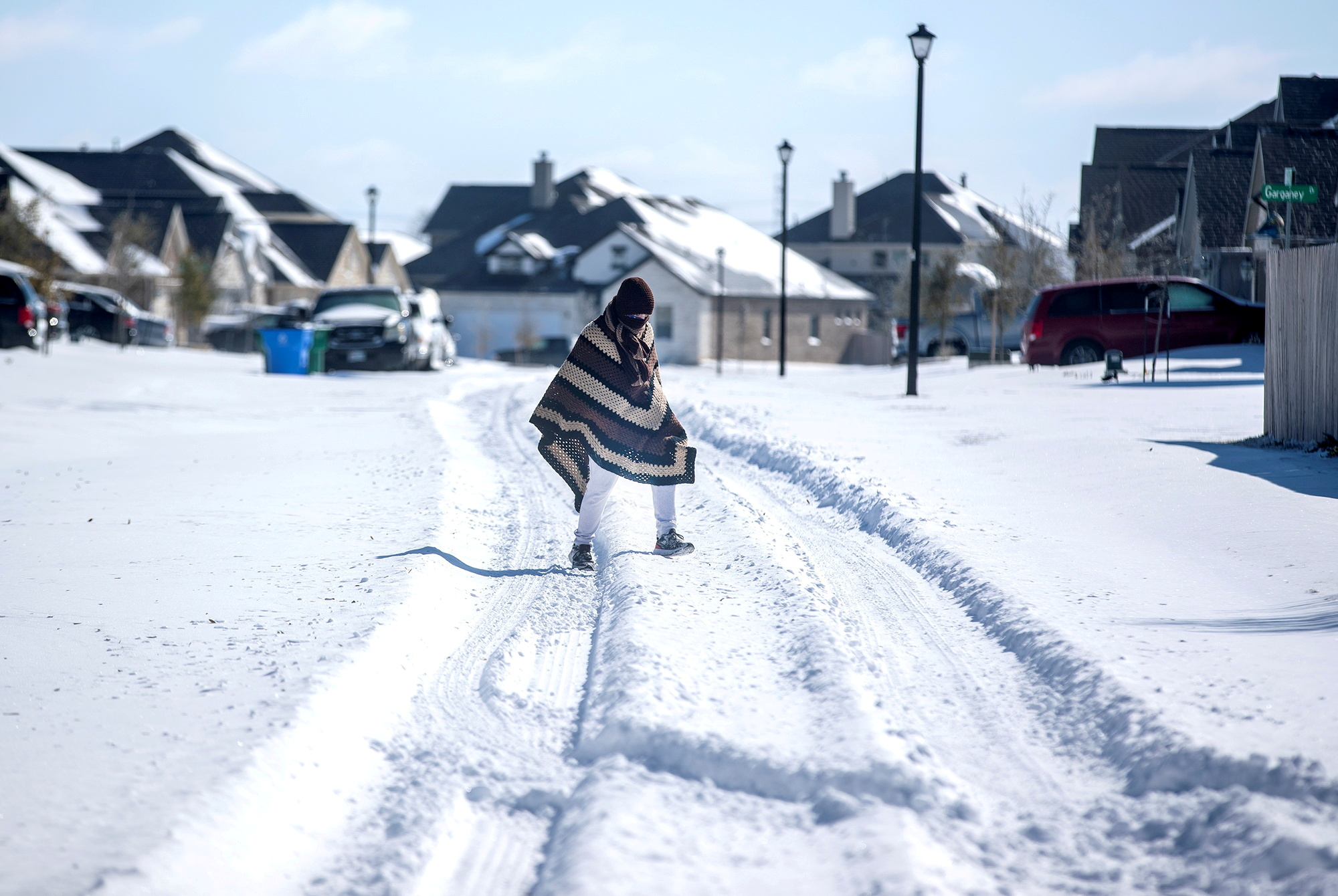 FILE PHOTO: A man walks to his friend's home in a neighbourhood without electricity as snow covers the BlackHawk neighborhood in Pflugerville, Texas, U.S. February 15, 2021. Picture taken February 15, 2021.   Bronte Wittpenn