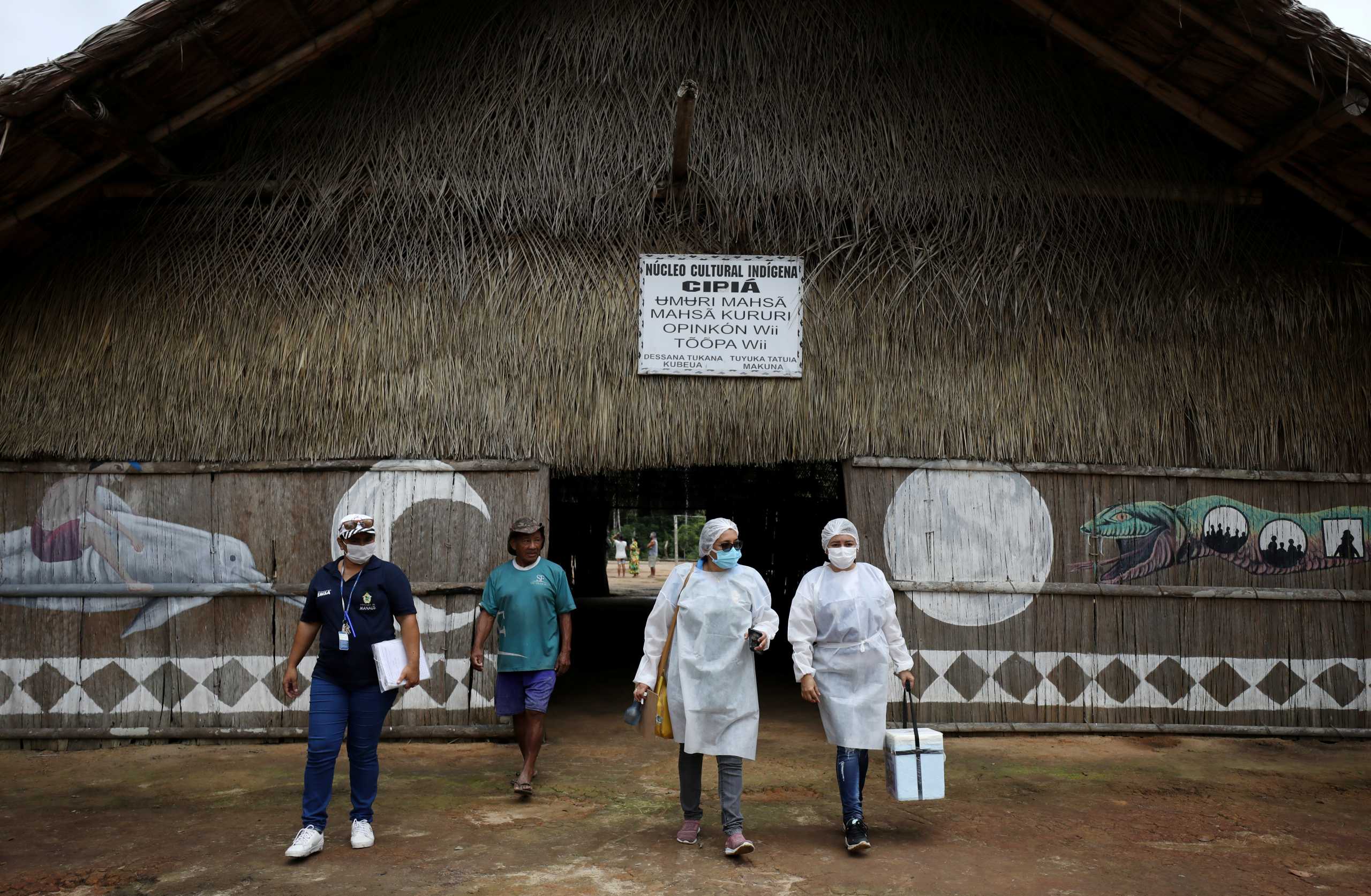 Municipal health workers leave an Indigenous hut after administering the AstraZeneca