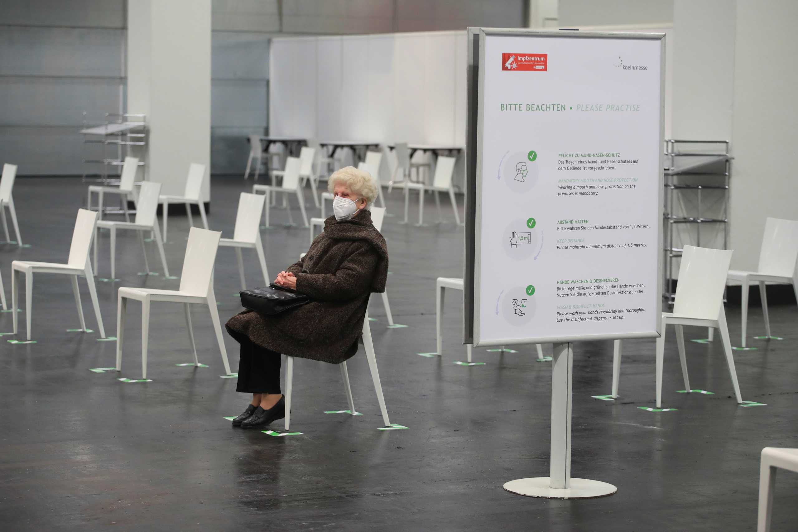 An elderly woman wearing a protective face mask waits to receive the Pfizer-BioNTech COVID-19 vaccine, at a vaccination centre temporarily set up in a hall of the fair of Cologne, Germany, February 8, 2021. REUTERS
