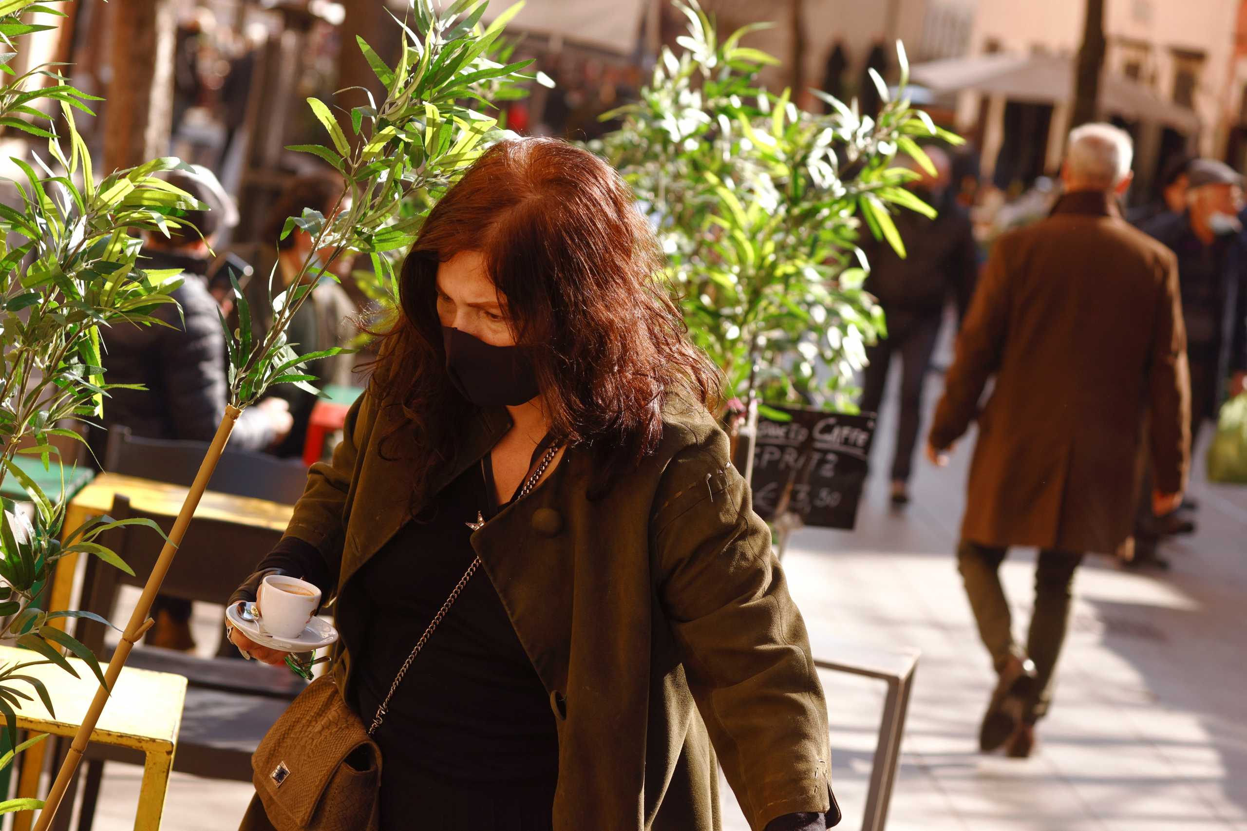 A woman carries a cup of coffee at a cafe after the coronavirus disease (COVID-19) restrictions were eased in Lazio region, in Rome, Italy, February 2, 2021. REUTERS