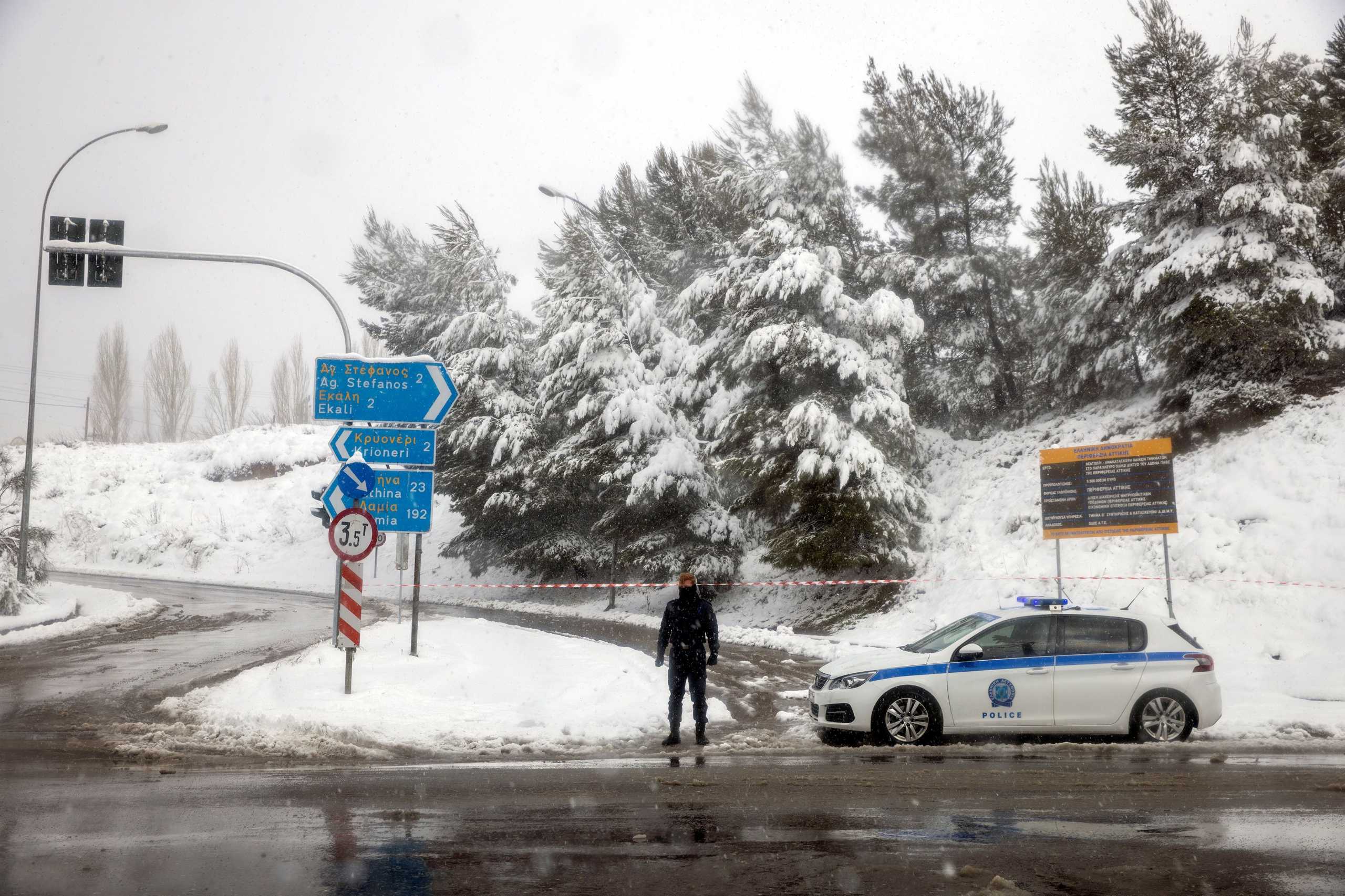 A police officer stands guard at an exit point to the national highway, which is closed due to heavy snowfall, near the village of Krioneri, Greece, February 15, 2021. REUTERS