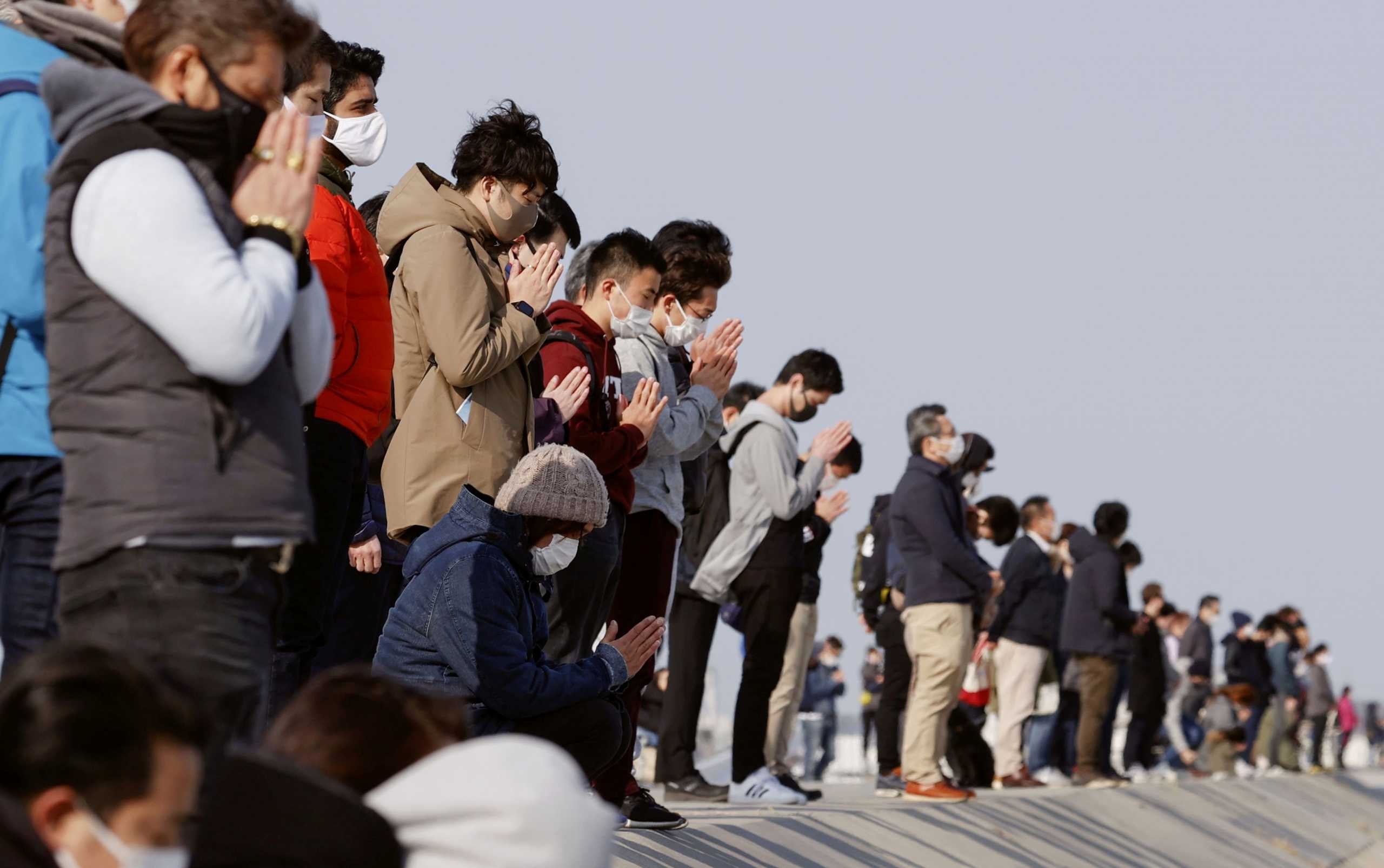 Participants pray and observe a moment of silence towards the sea at 2:46 p.m. (05:46 GMT), the time when the 9.0-magnitude earthquake struck off Japan's coast in 2011, at Arahama district in Sendai, northeastern Japan, March 11, 2021, to mark the 10-year anniversary of the 2011 earthquake and tsunami that killed thousands and set off a nuclear crisis.  Mandatory credit Kyodo