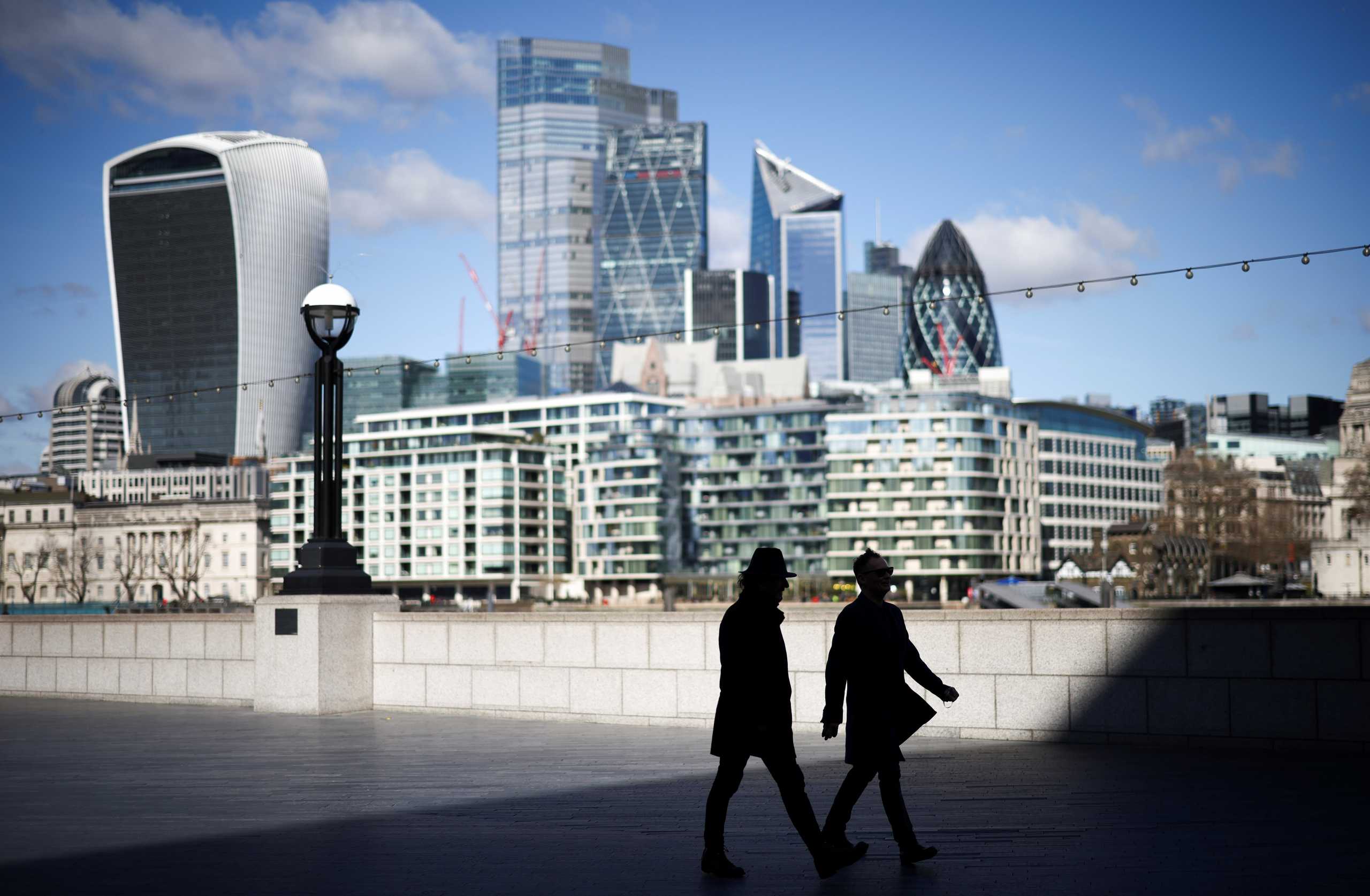 The City of London financial district can be seen as people walk along the south side of the River Thames, amid the coronavirus disease (COVID-19) outbreak in London, Britain, March 19, 2021. REUTERS