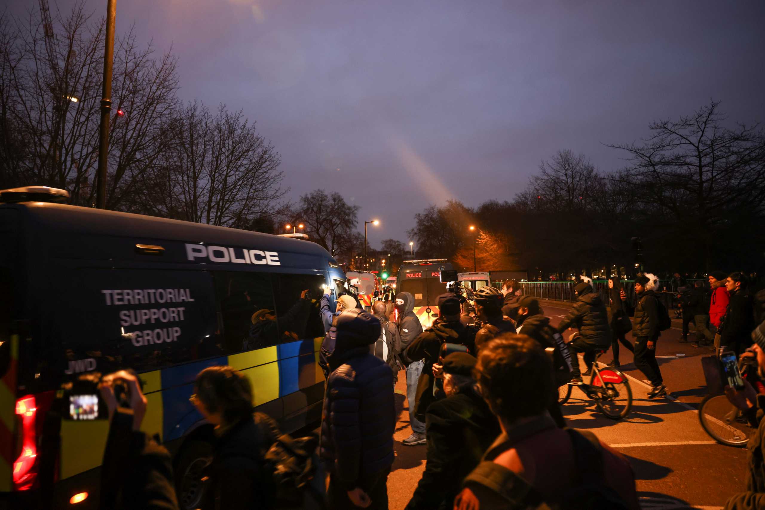 People stand next to a police vehicle during a protest against the lockdown, amid the spread of the coronavirus disease (COVID-19), in London, Britain March 20, 2021. REUTERS
