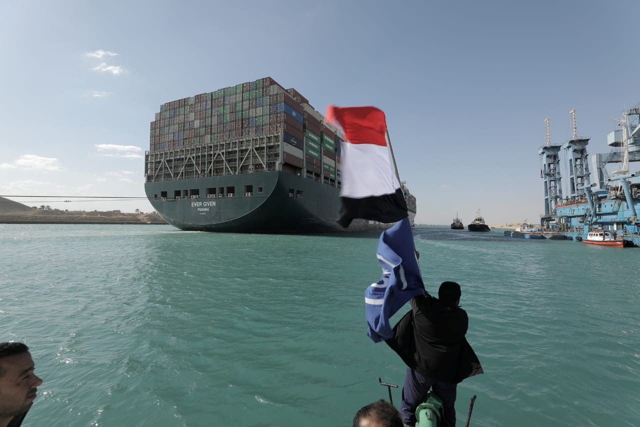 A man waves an Egyptian flag as ship Ever Given, one of the world's largest container ships, is seen after it was fully floated in Suez Canal, Egypt March 29, 2021.  Suez Canal Authority