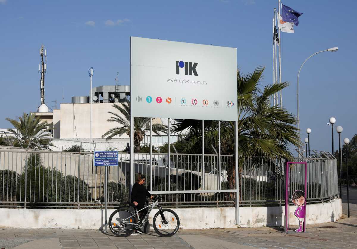 A woman walks with her bicycle outside the Cyprus Broadcasting Corporation headquarters in Nicosia, Cyprus February 26, 2021. REUTERS