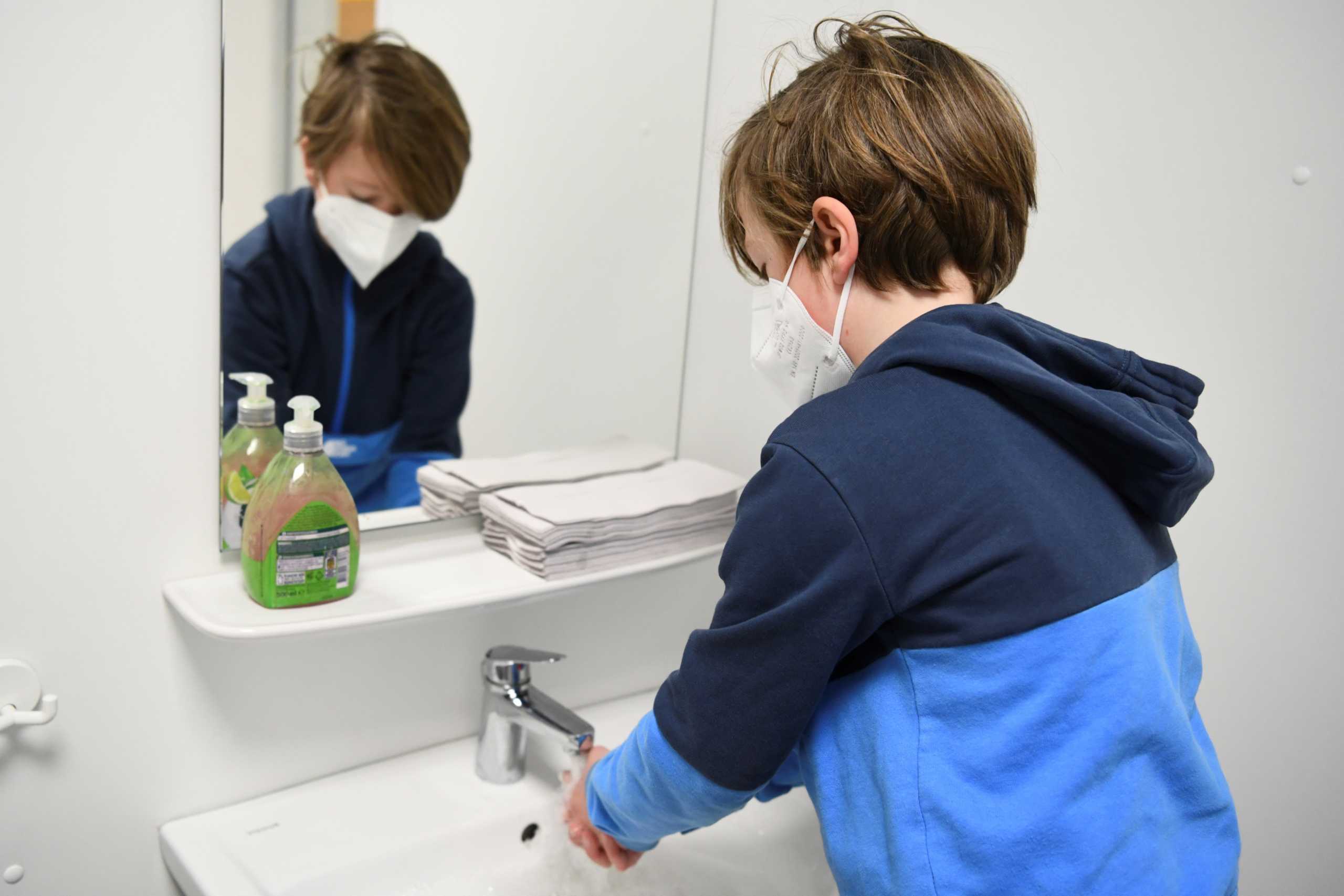 A schoolchild washes his hands before participating in a lesson at Gustav-Falke elementary school, after it reopened according to first measures to lift the coronavirus disease (COVID-19) lockdown in Berlin, Germany, February 22, 2021.  REUTERS