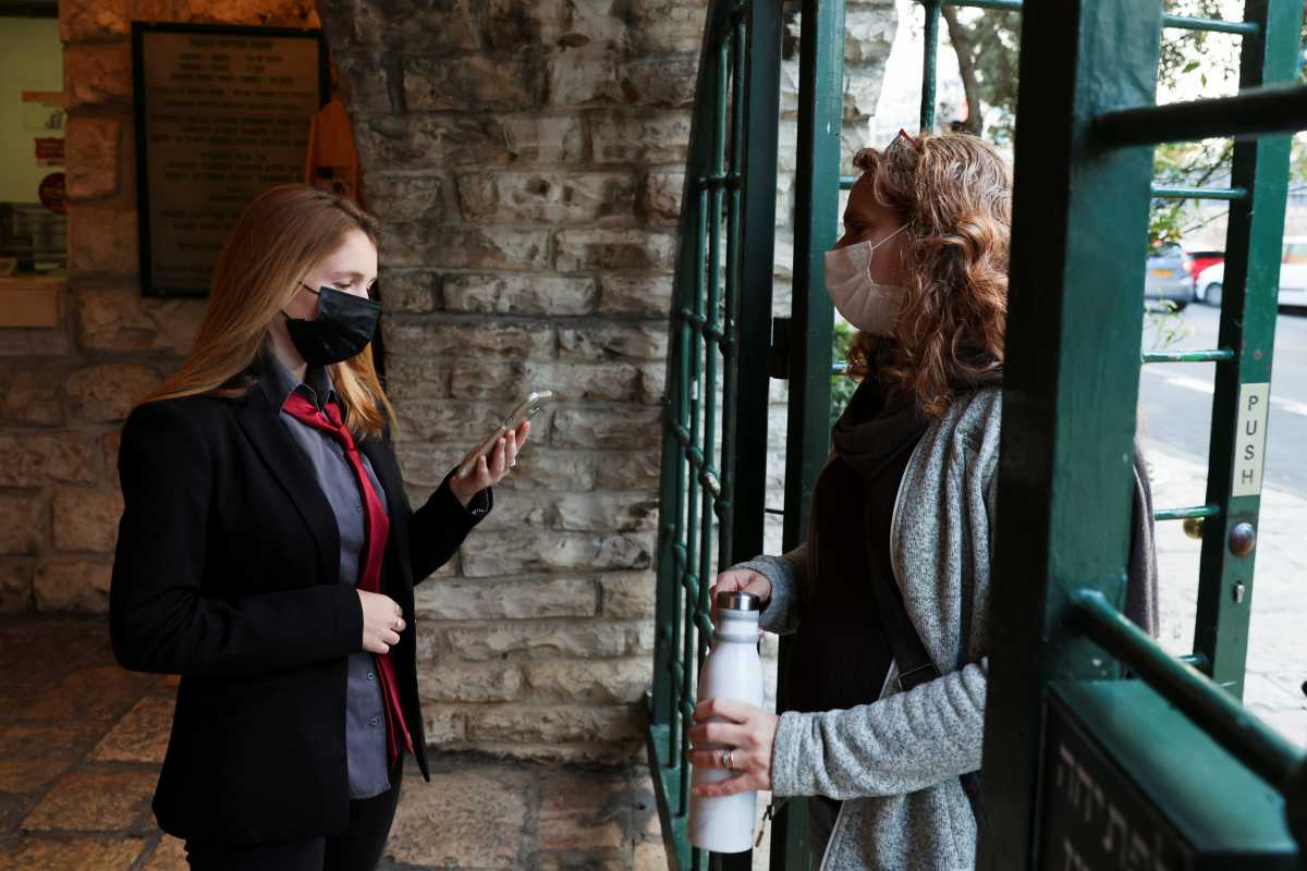 A woman shows her "Green Pass", a pass for those vaccinated against the coronavirus disease (COVID-19) or those with presumed immunity, as she enters a show at the Khan Theatre in Jerusalem February 25, 2021. Picture taken February 25, 2021. REUTERS