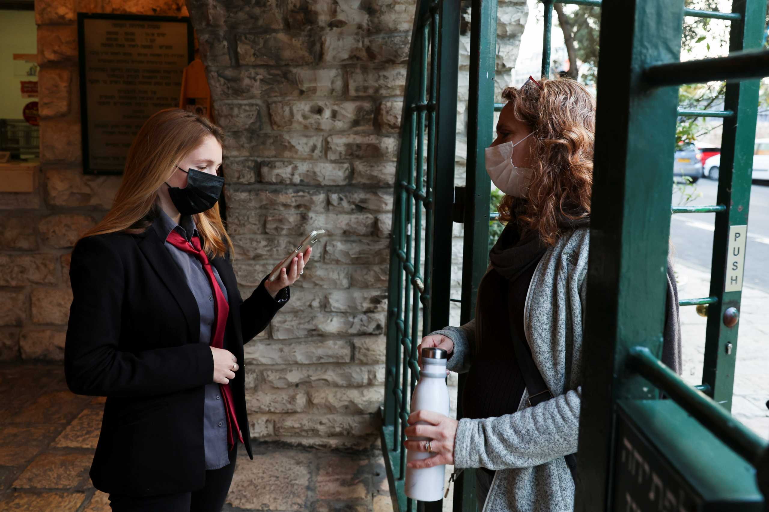 A woman shows her "Green Pass", a pass for those vaccinated against the coronavirus disease (COVID-19) or those with presumed immunity, as she enters a show at the Khan Theatre in Jerusalem February 25, 2021. Picture taken February 25, 2021. REUTERS