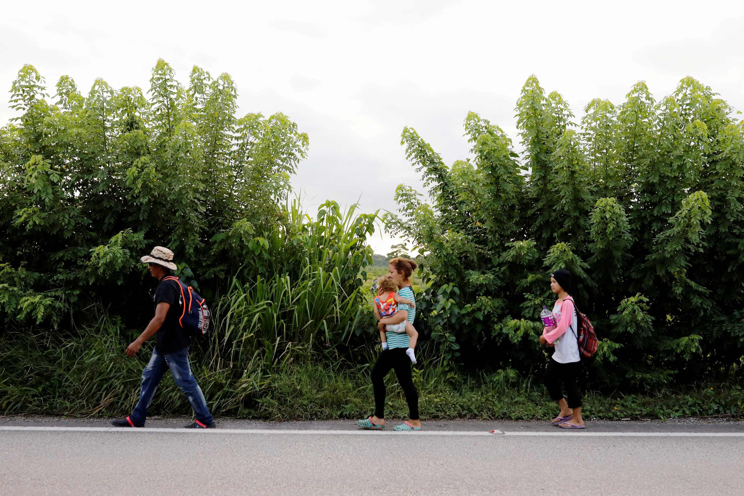 FILE PHOTO: Honduran migrants trying to reach the U.S. walk along a road as they move towards the Mexico border, in San Pedro Cadenas, Guatemala October 3, 2020. REUTERS
