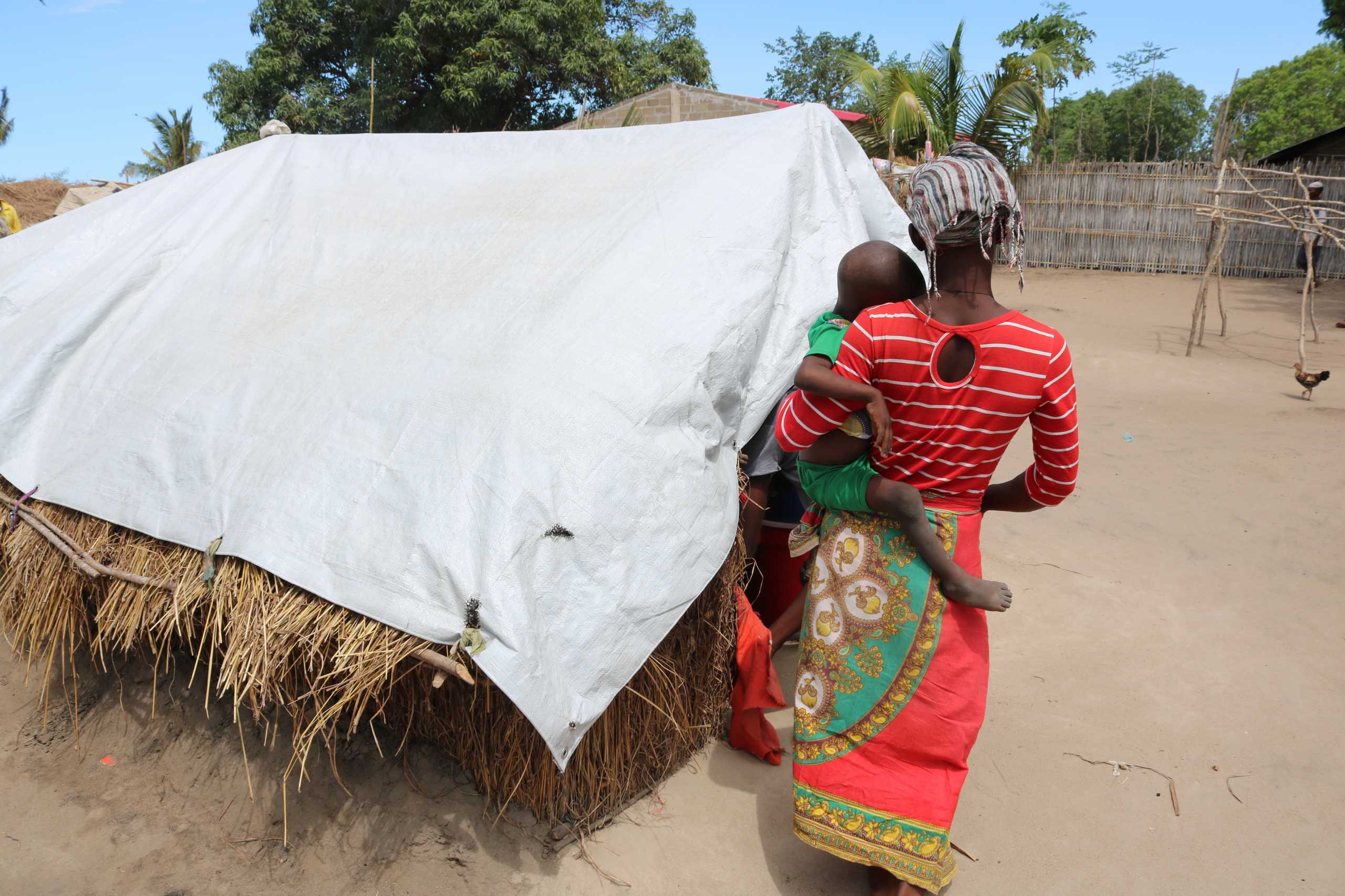 A woman, called Elsa by UK-based aid group Save the Children, walks with a child in a displacement camp in the northern Mozambique province of Cabo Delgado, in this handout picture taken January 26, 2021. Rui Mutemba