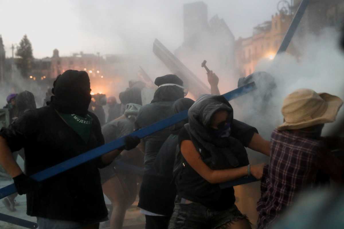 People try to take down the fences placed outside the National Palace during a protest on International Women's Day, in Mexico City, Mexico, March 8, 2021. REUTERS