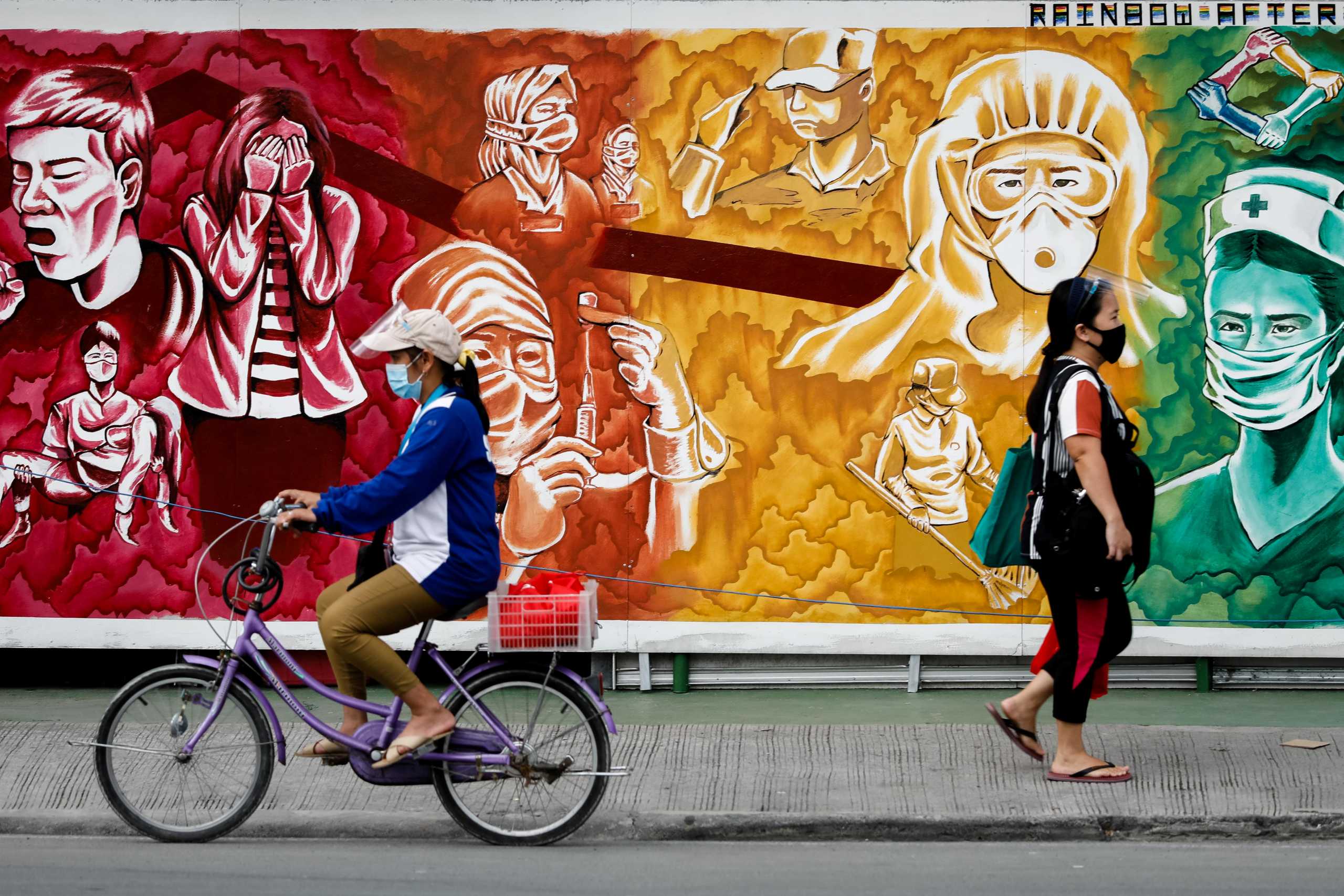 FILE PHOTO: People wearing masks for protection against the coronavirus disease (COVID-19) pass a mural dedicated to healthcare workers, in Pasig City, Metro Manila, Philippines, October 30, 2020. REUTERS