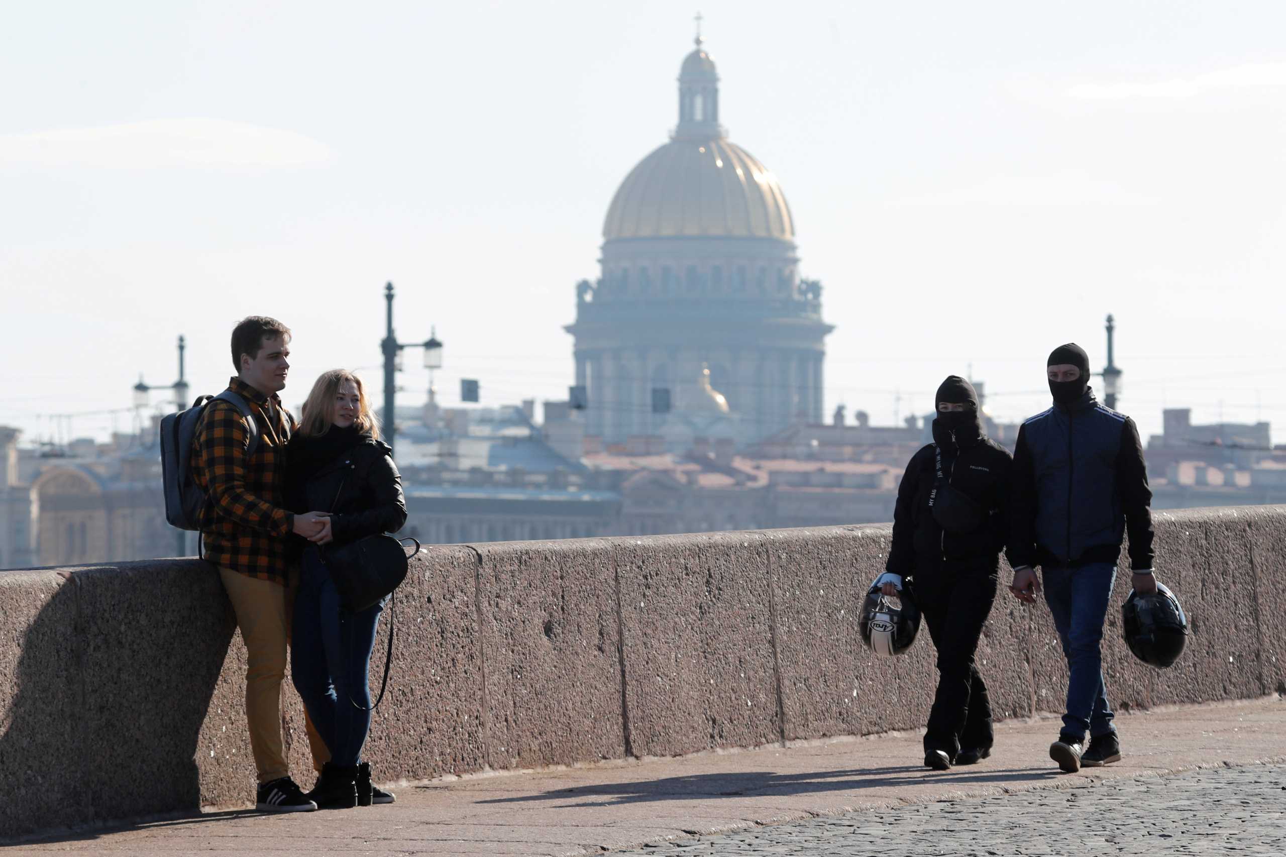 FILE PHOTO: People rest on the Spit of Vasilievsky Island with the St. Isaac's Cathedral in the background on the first day of holidays ordered by President Vladimir Putin to curb the spread of the coronavirus disease (COVID-19), in central Saint Petersburg, Russia March 28, 2020.  REUTERS