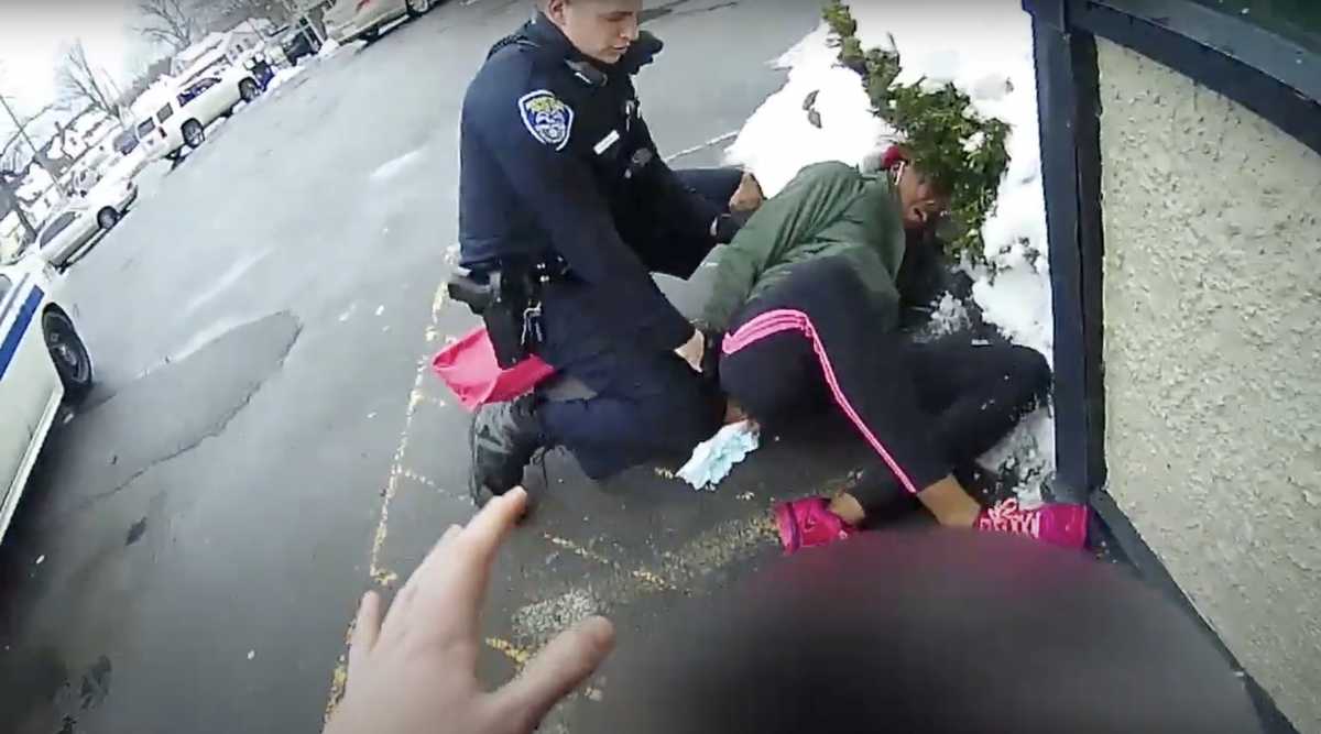 A police officer detains a woman as another officer holds her child in Rochester, New York, U.S., February 22, 2021 in this frame grab taken from police body cam footage.  Rochester Police Department