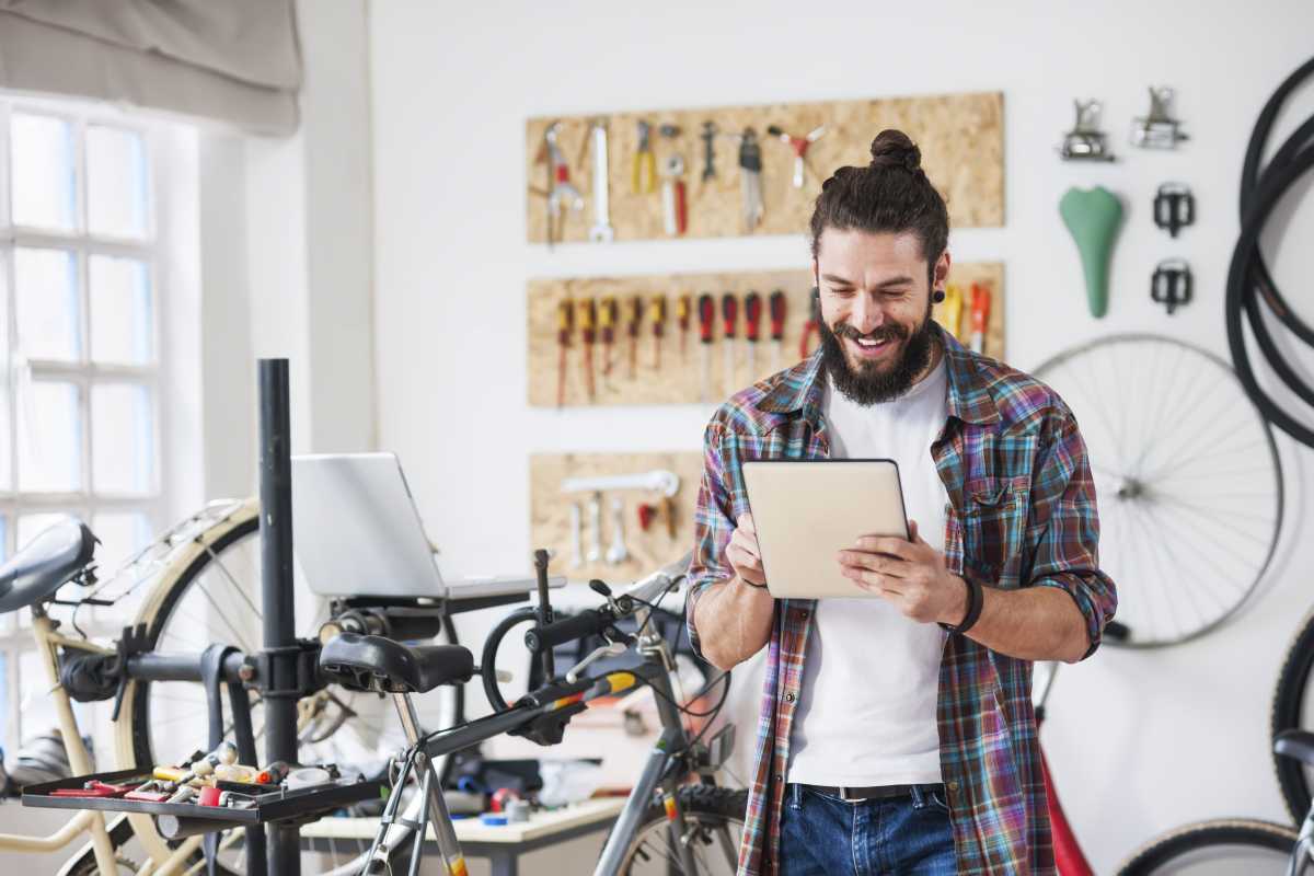Young man working at his bike service, using digital tablet