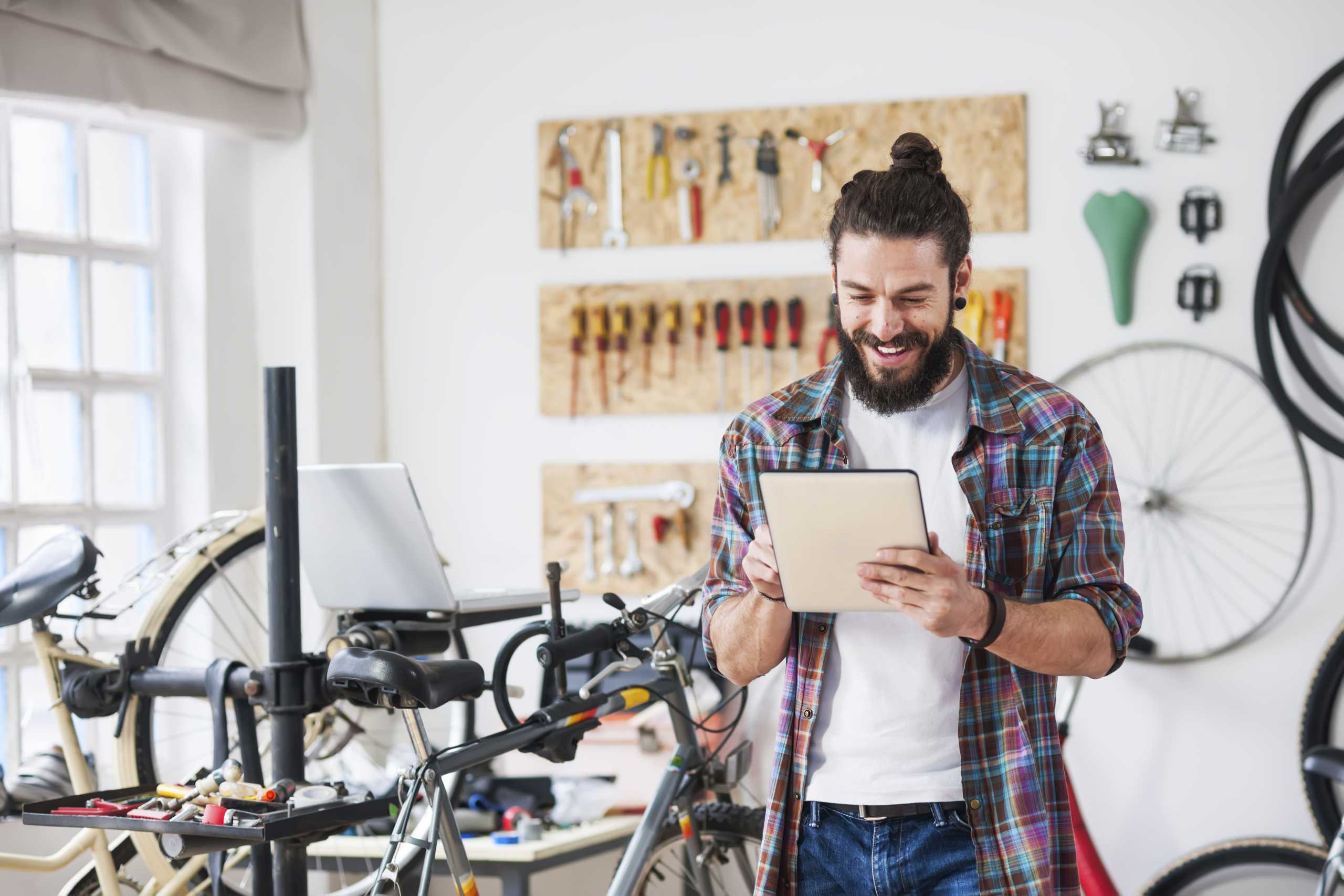Young man working at his bike service, using digital tablet