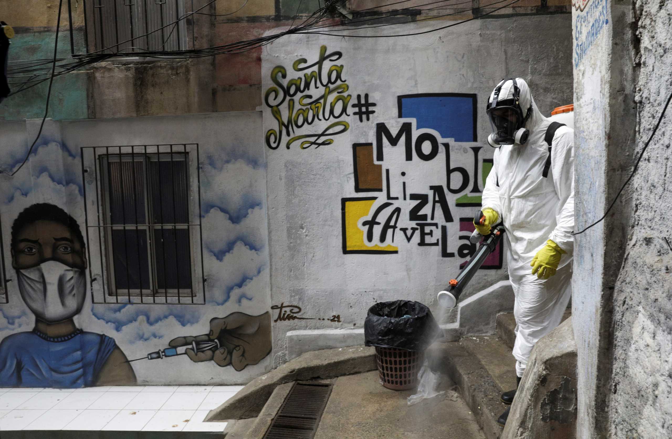 A volunteer disinfects the alleys of Santa Marta slum during the coronavirus disease (COVID-19) outbreak, in Rio de Janeiro, Brazil March 13, 2021. REUTERS