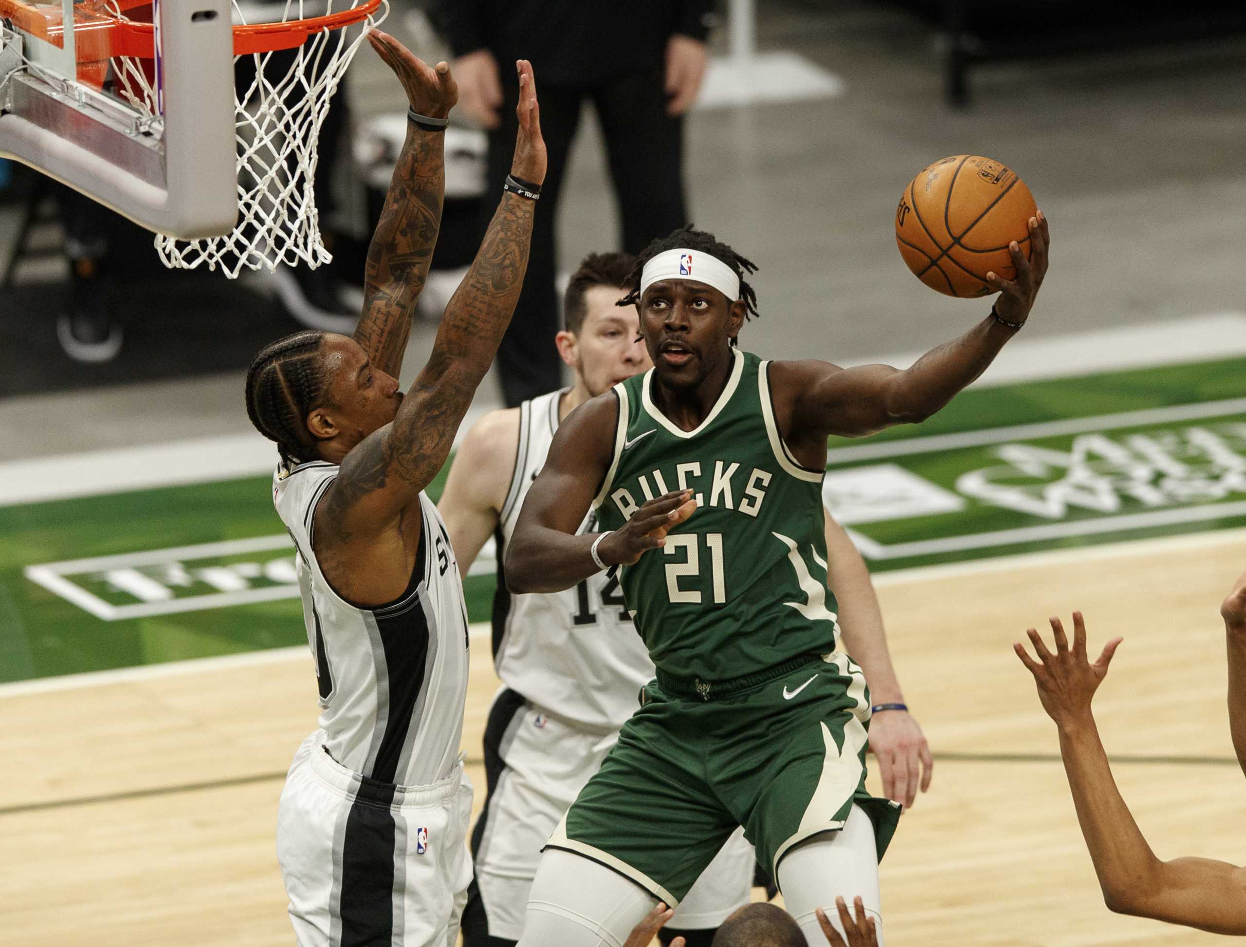 Mar 20, 2021; Milwaukee, Wisconsin, USA;  Milwaukee Bucks guard Jrue Holiday (21) shoots against San Antonio Spurs guard DeMar DeRozan (10) during the first quarter at Fiserv Forum. Mandatory Credit: Jeff Hanisch-USA TODAY Sports
