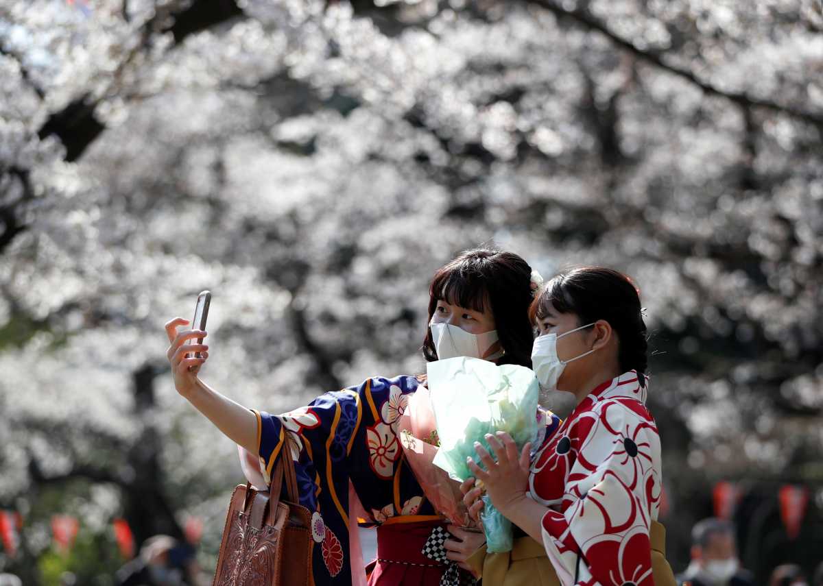 Kimono-clad women wearing protective face masks take selfie photos among blooming cherry blossoms amid the coronavirus disease (COVID-19) panemic, at Ueno Park in Tokyo, Japan, March 23, 2021.  REUTERS