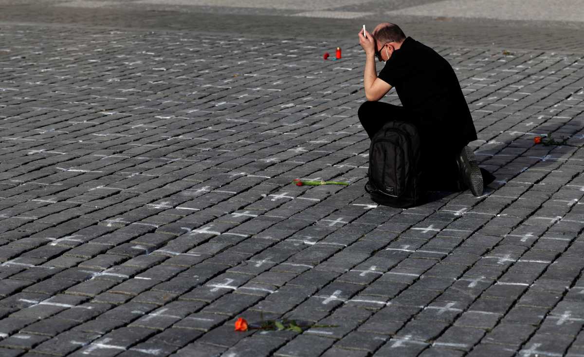 A man mourns for his deceased loved one at the Old Town Square where thousands of crosses have been painted on a pavement to commemorate the first anniversary since the death of the first Czech coronavirus disease (COVID-19) patient in Prague, Czech Republic, March 25, 2021. Picture taken March 25, 2021. REUTERS