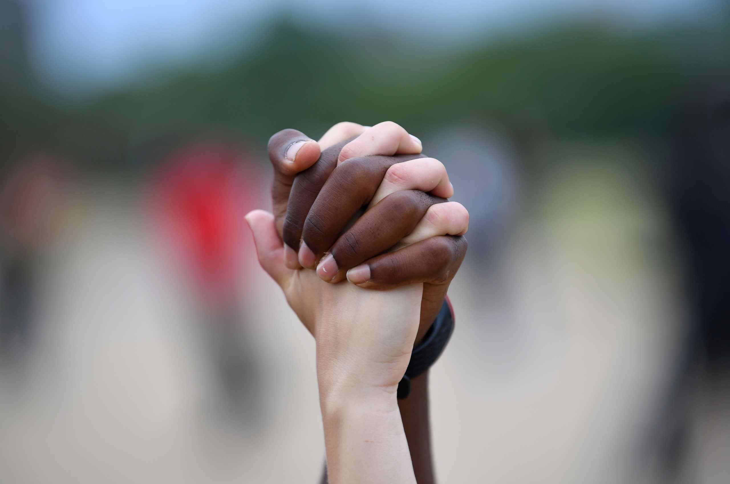 FILE PHOTO: A man and a woman hold hands aloft in Hyde Park during a "Black Lives Matter" protest following the death of George Floyd who died in police custody in Minneapolis, London, Britain, June 3, 2020. REUTERS