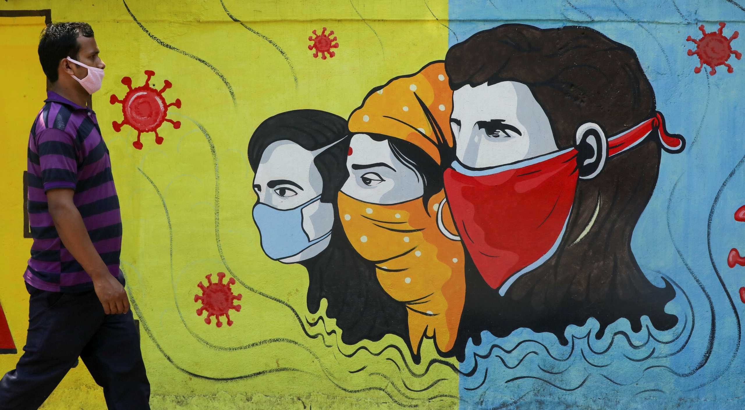 FILE PHOTO: A man wearing a protective mask walks past a graffiti amidst the spread of the coronavirus disease (COVID-19) on a street in Navi Mumbai, India, March 8, 2021. REUTERS