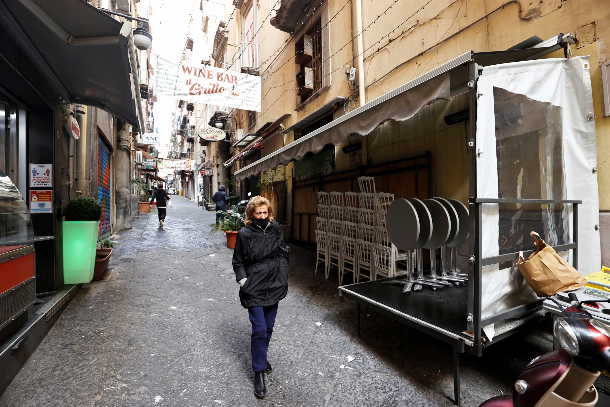 A woman walks past empty chairs and tables of a closed restaurant after the region of Campania became a "red zone", increasing restrictions due to a rise in the coronavirus disease (COVID-19) infections, in Naples, Italy, March 8, 2021. REUTERS