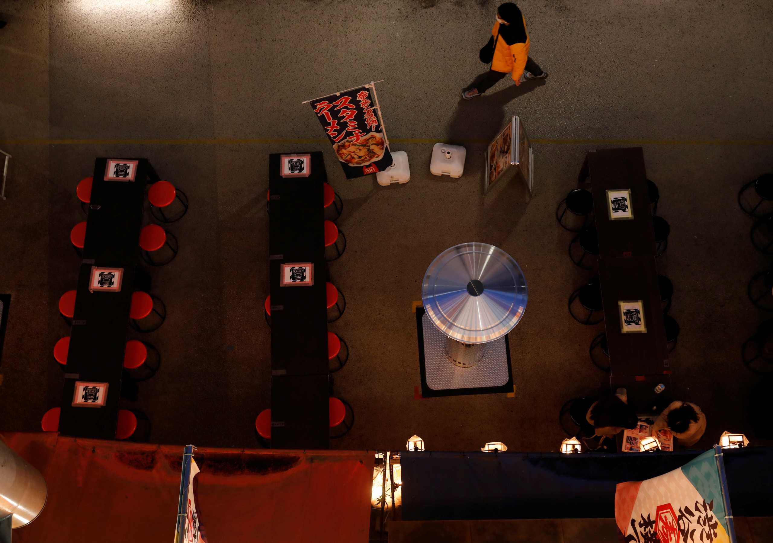 A man wearing a protective mask, amid the coronavirus disease (COVID-19) outbreak, walks past empty tables at restaurants underneath Miyashita Park at Shibuya in Tokyo, Japan, March 9, 2021. Picture taken on March 9, 2021. REUTERS