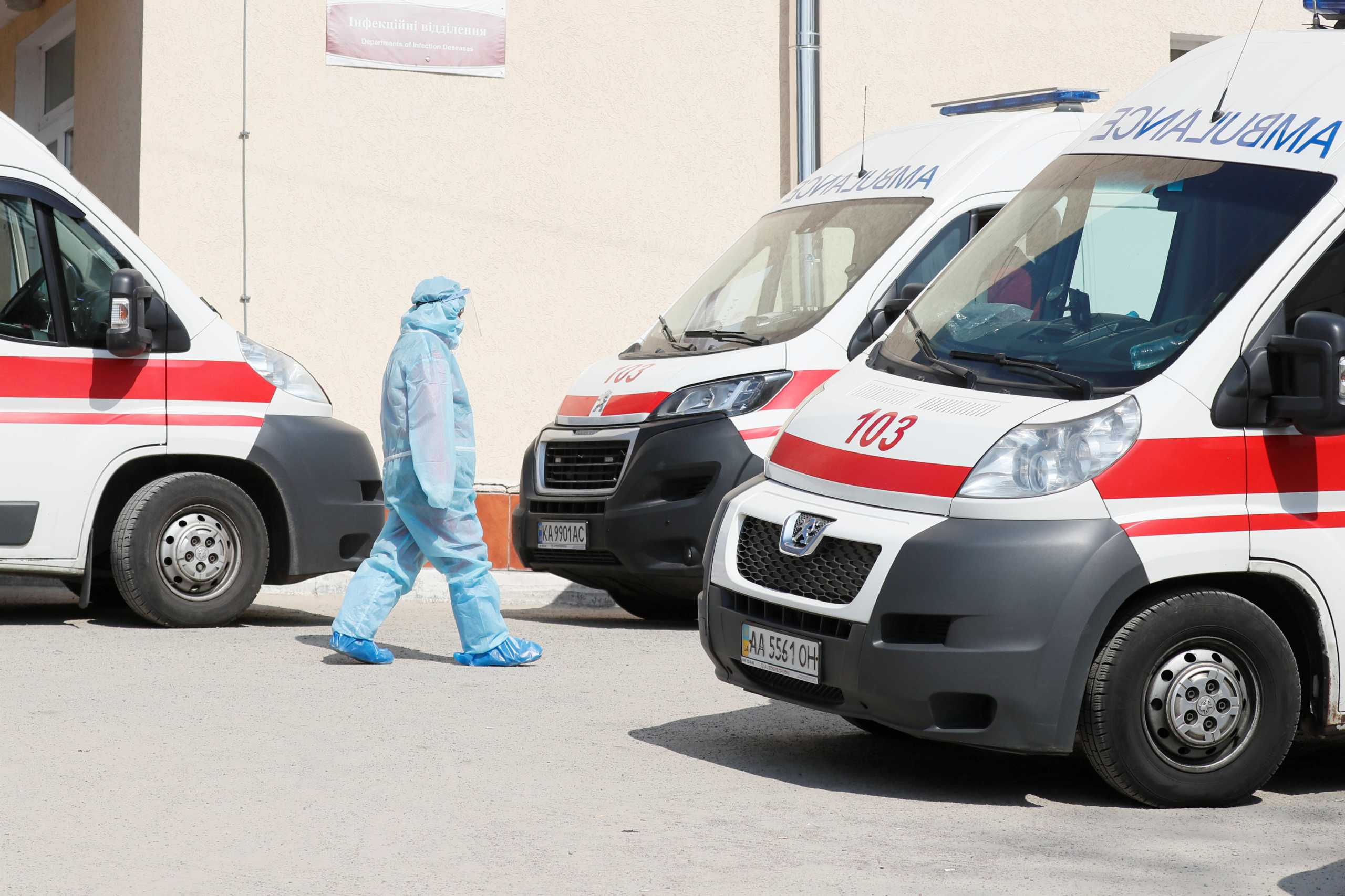 A health worker is seen near ambulances with COVID-19 patients as they wait in the queue at a hospital for people infected with coronavirus disease in Kyiv, Ukraine March 30, 2021.  REUTERS