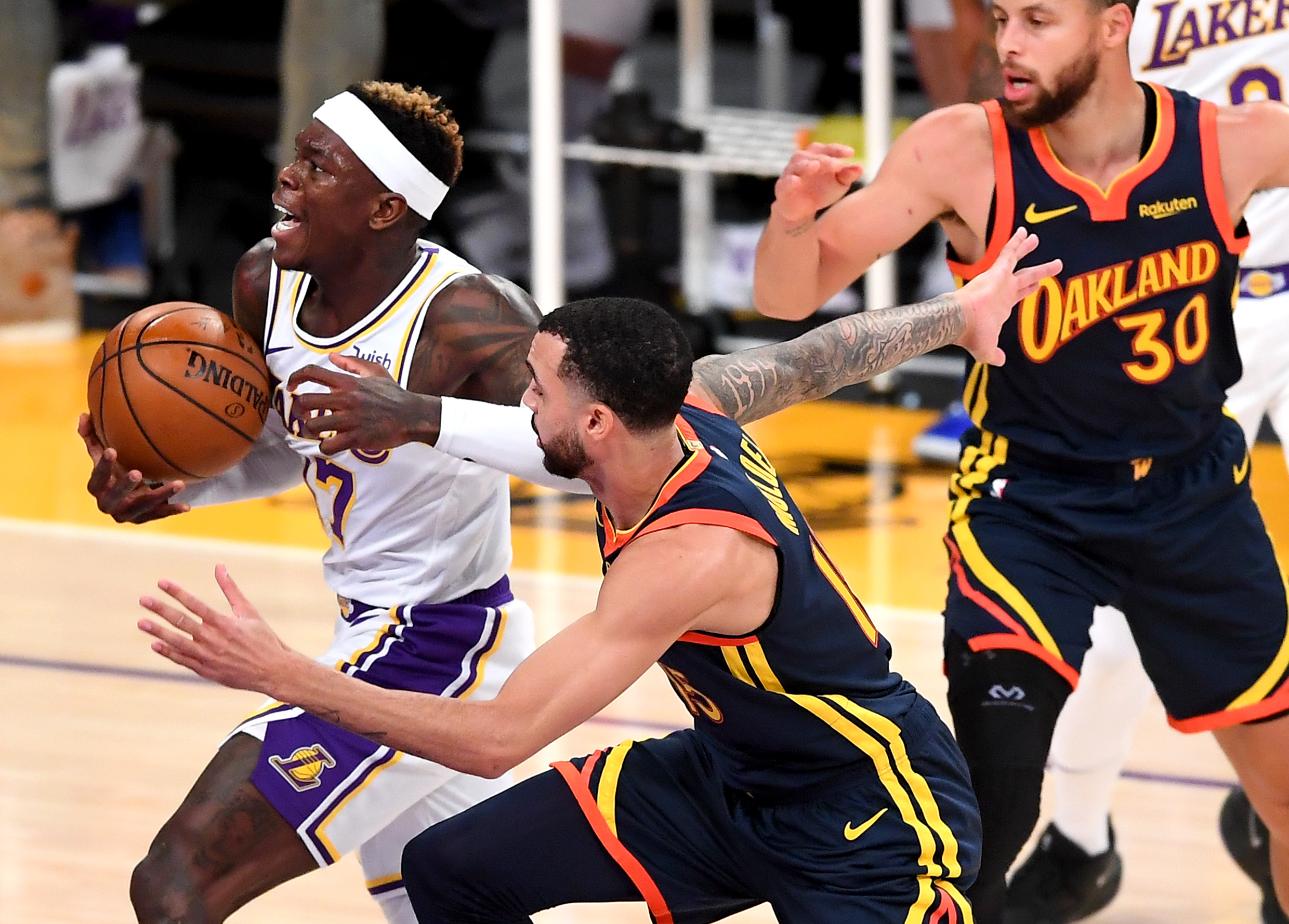 Feb 28, 2021; Los Angeles, California, USA;  Los Angeles Lakers guard Dennis Schroder (17) gets past Golden State Warriors guard Stephen Curry (30) and guard Mychal Mulder (15) for a basket in the first half of the game at Staples Center. Mandatory Credit: Jayne Kamin-Oncea-USA TODAY Sports